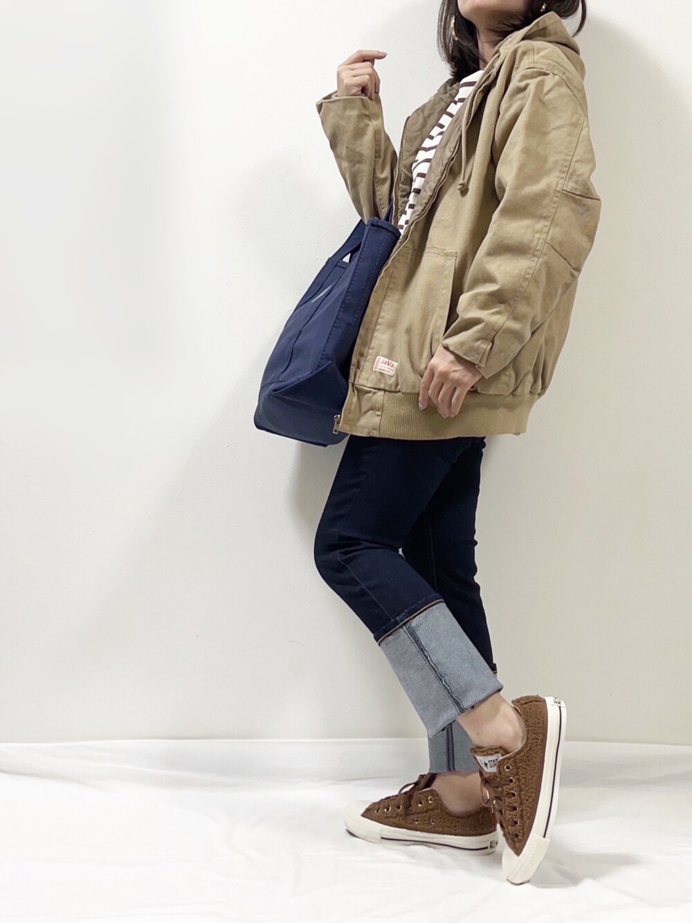 ベージュ系のブルゾン、ブルー系のデニムパンツ、ブラウン系のスニーカーを着用したレディースの秋コーディネートの2枚目の写真