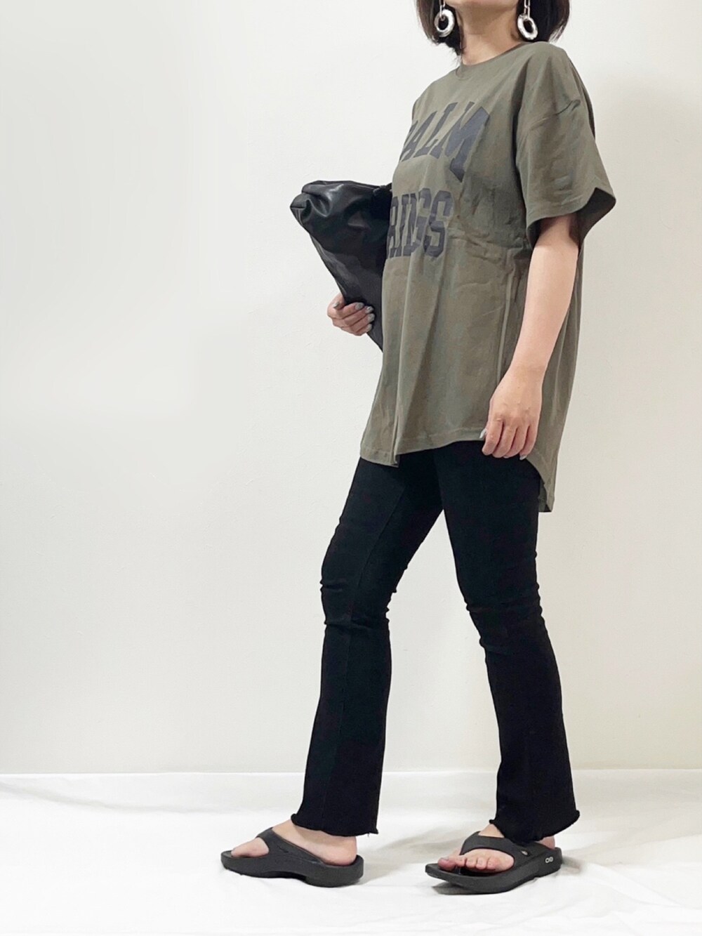 グリーン系のTシャツ/カットソー、ブラック系のデニムパンツ、ブラック系のサンダルを着用したレディースの夏コーディネートの2枚目の写真