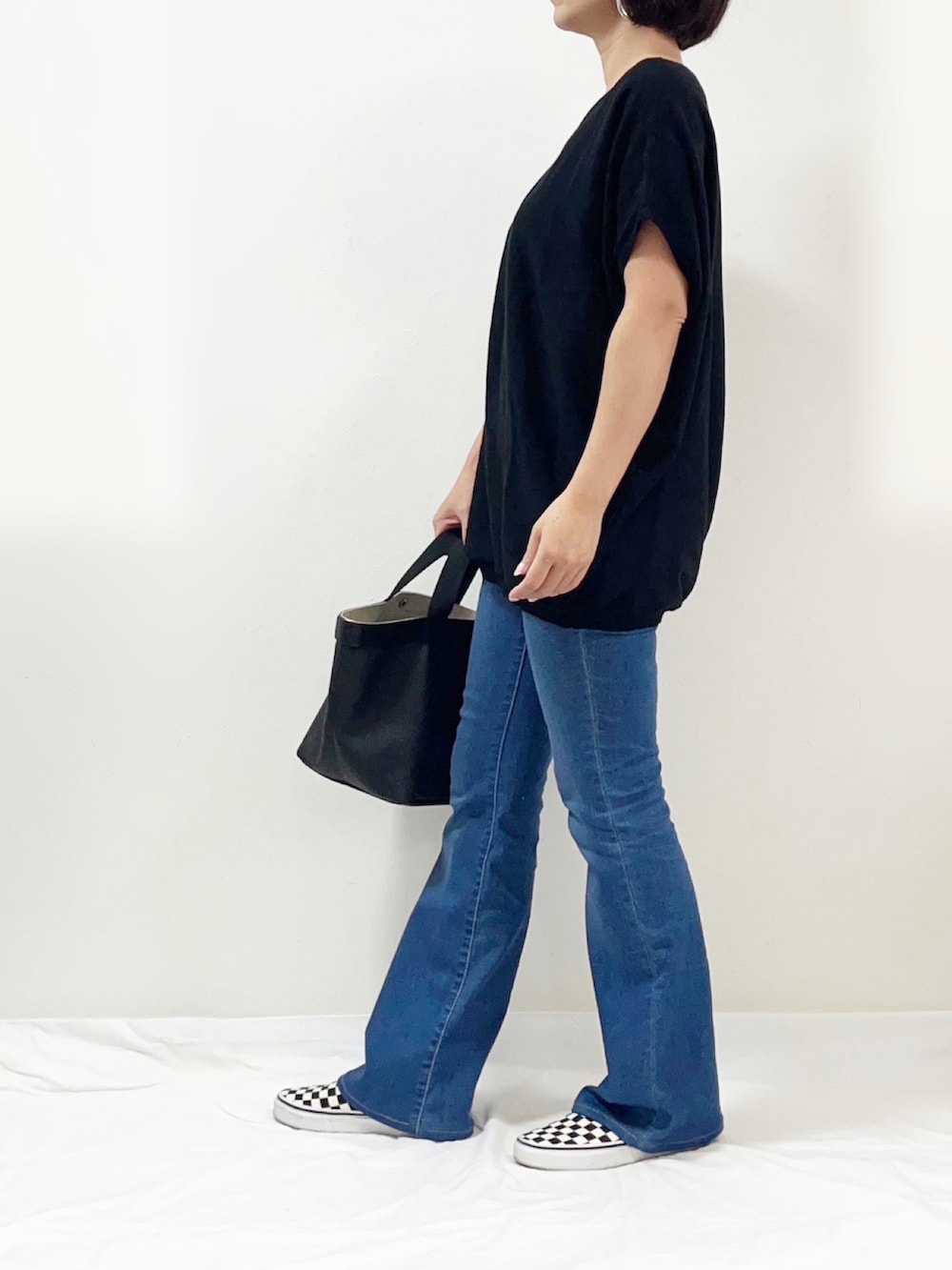 ブラック系のニット/セーター、ブルー系のデニムパンツ、ブラック系のスリッポンを着用したレディースの秋コーディネートの2枚目の写真