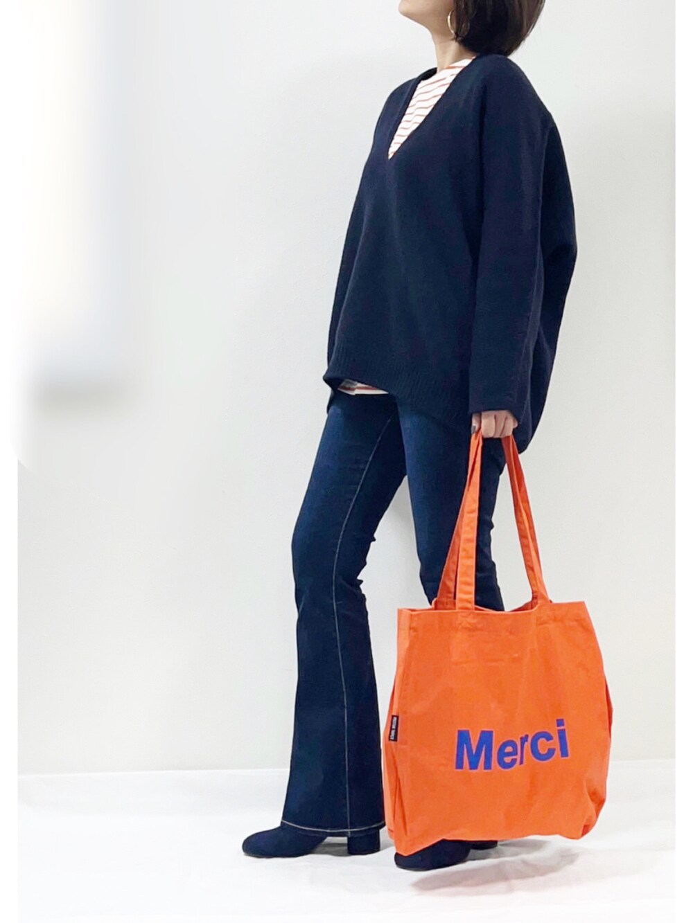 オレンジ系のTシャツ/カットソー、ブルー系のニット/セーター、ブルー系のデニムパンツを着用したレディースの冬コーディネートの2枚目の写真