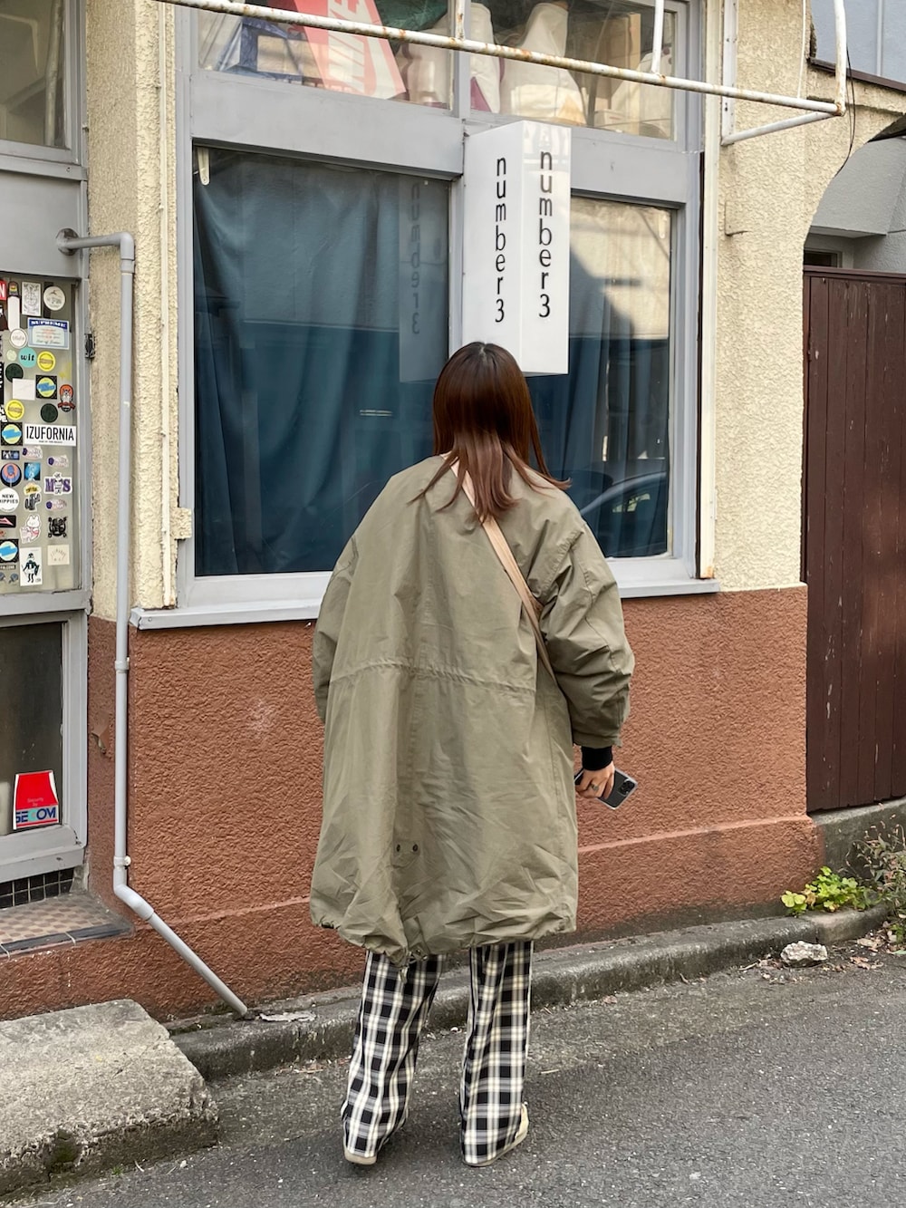 グリーン系のモッズコート、ベージュ系のモカシン/デッキシューズ、ブラック系のスウェットを着用したレディースの冬コーディネートの2枚目の写真