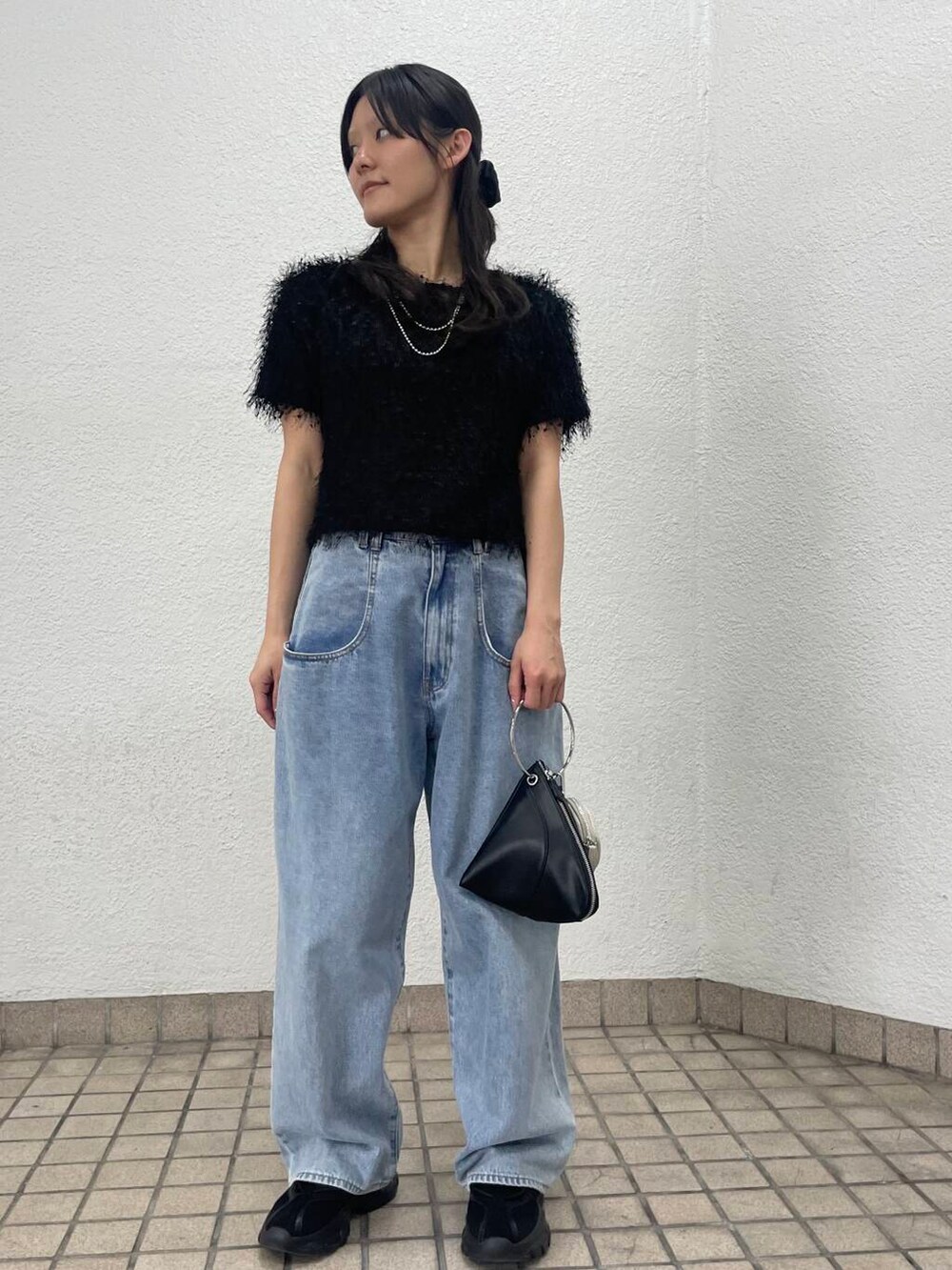 ブルー系のデニムパンツ、ブラック系のハンドバッグ、ブラック系のTシャツ/カットソーを着用したレディースの夏コーディネートの2枚目の写真