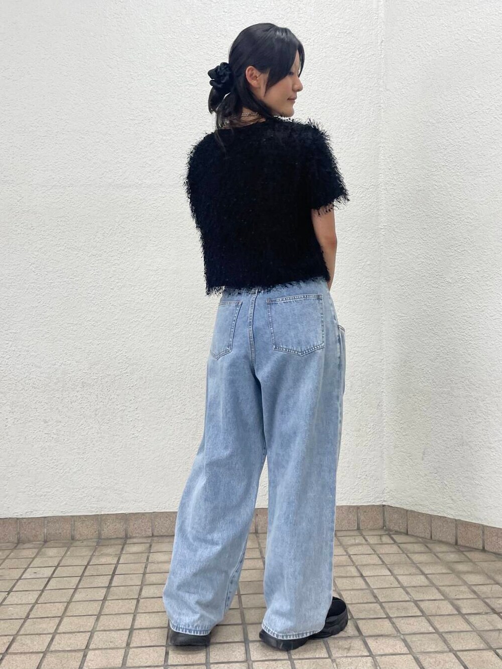 ブルー系のデニムパンツ、ブラック系のハンドバッグ、ブラック系のTシャツ/カットソーを着用したレディースの夏コーディネートの3枚目の写真