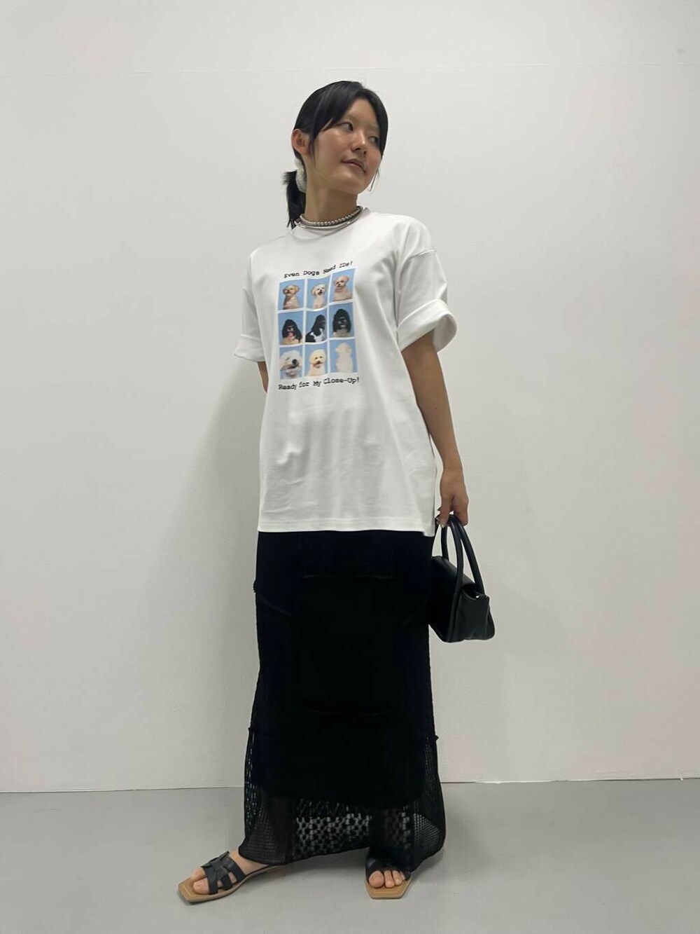 ブラック系のスカート、ホワイト系のTシャツ/カットソー、シルバー系のネックレスを着用したレディースの夏コーディネートの2枚目の写真
