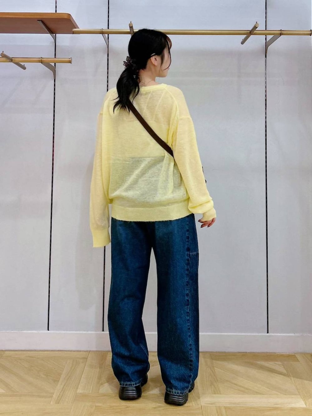 ブルー系のデニムパンツ、ブラウン系のスニーカー、ブラウン系のショルダーバッグを着用したレディースの秋コーディネートの2枚目の写真