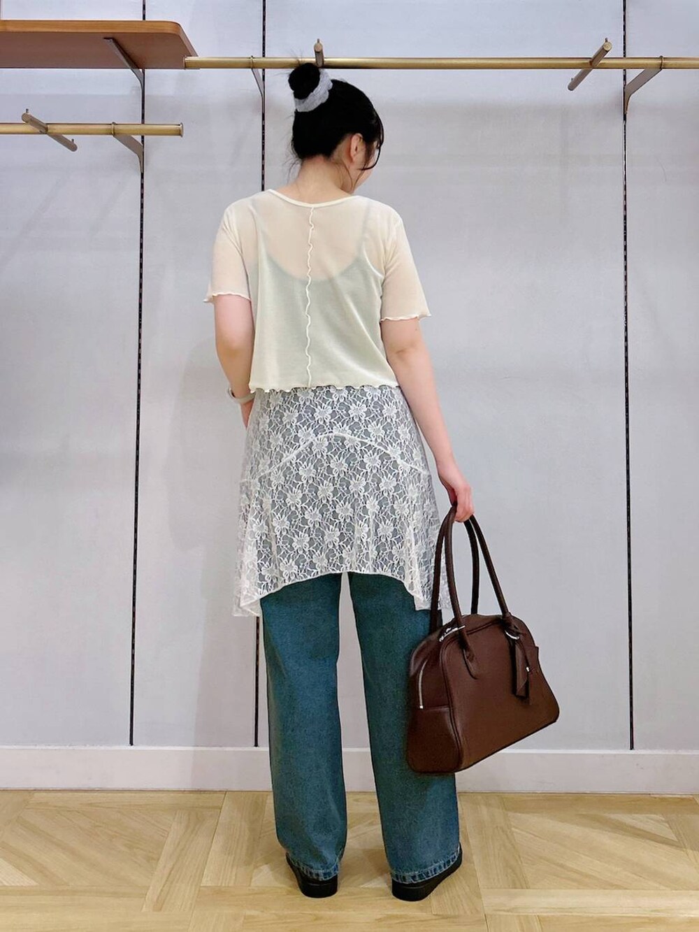 ブルー系のデニムパンツ、シルバー系のサンダル、ホワイト系のスカートを着用したレディースの夏コーディネートの2枚目の写真