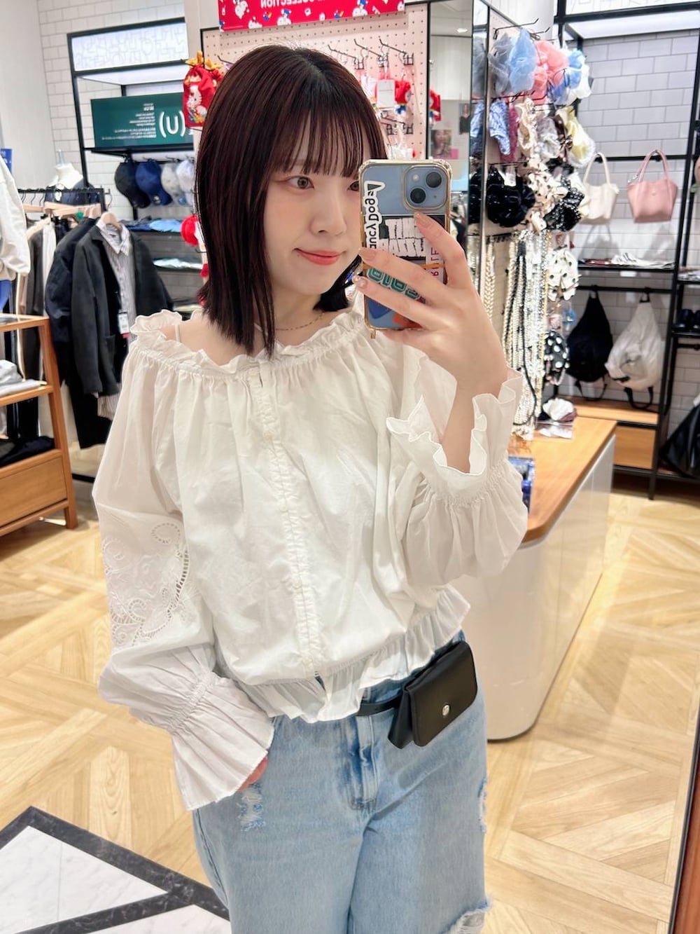 ブルー系のデニムパンツ、ホワイト系のシャツ/ブラウス、ブラック系のベルトを着用したレディースの春コーディネートの2枚目の写真