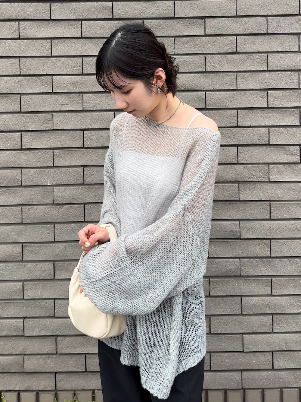 グレー系のニット/セーター、ブラック系のデニムパンツを着用したレディースの春コーディネートの2枚目の写真