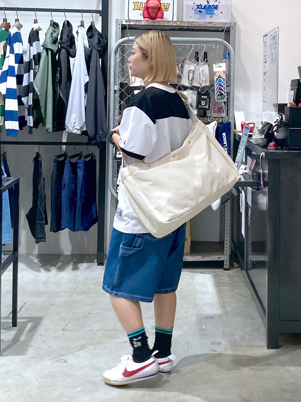 ブラック系のTシャツ/カットソー、ブルー系のその他パンツ、ホワイト系のショルダーバッグを着用したレディースの春コーディネートの2枚目の写真