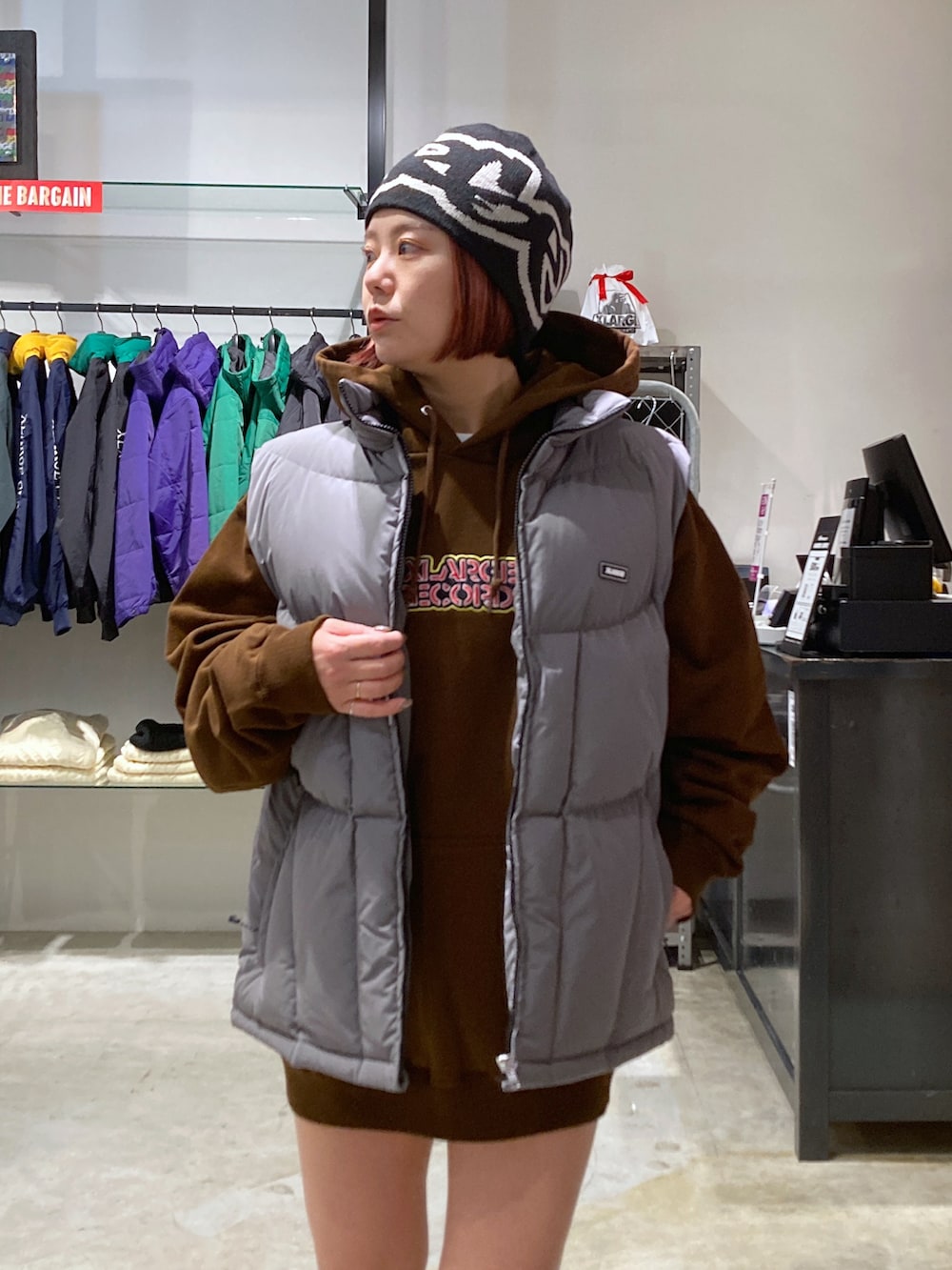 グレー系のダウンジャケット/コート、ブラウン系のパーカー、ブラック系のニットキャップ/ビーニーを着用したレディースの冬コーディネートの4枚目の写真