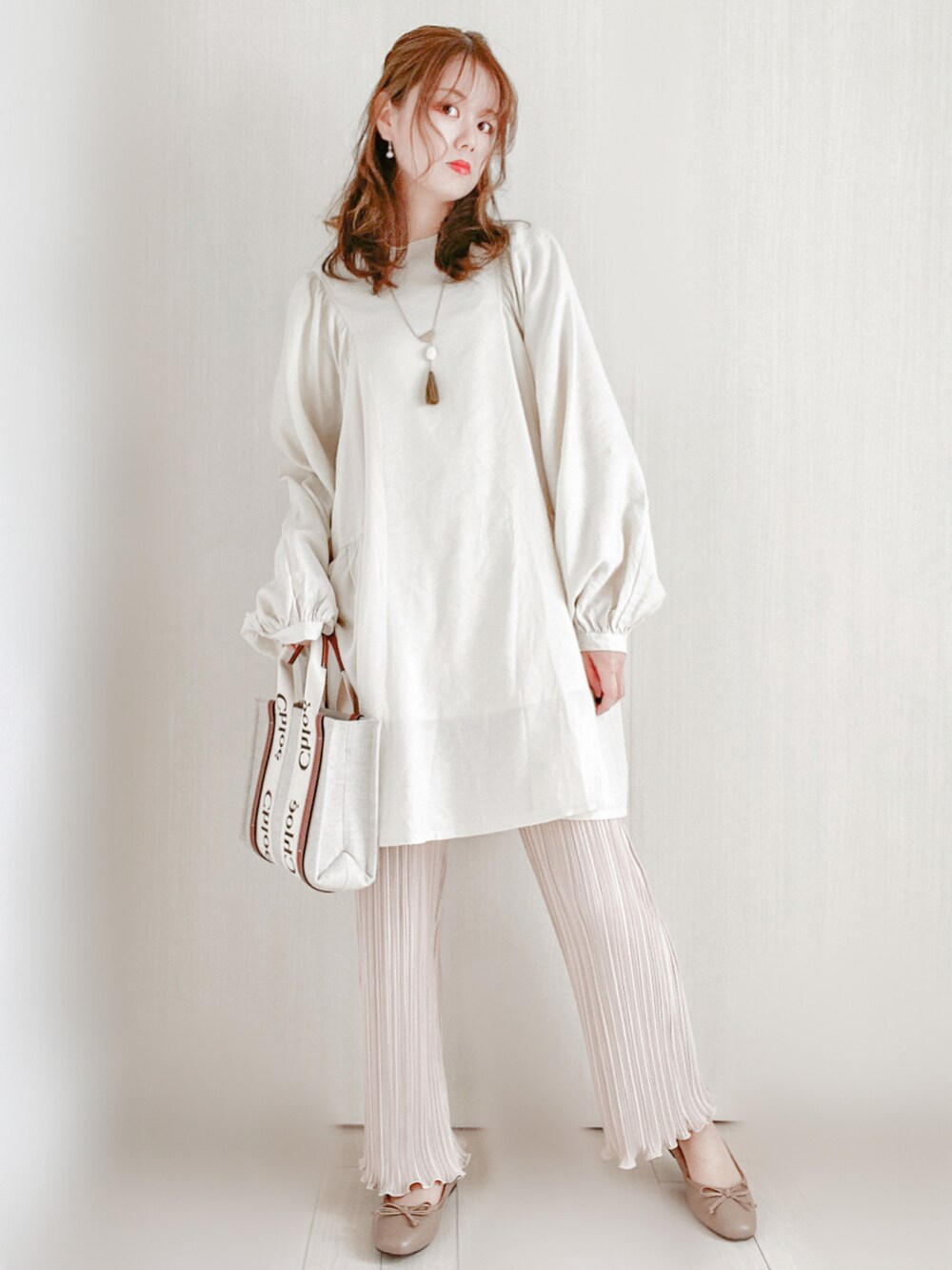 ブラウン系のトートバッグ、ベージュ系のバレエシューズ、ホワイト系のワンピースを着用したレディースの冬コーディネートの2枚目の写真