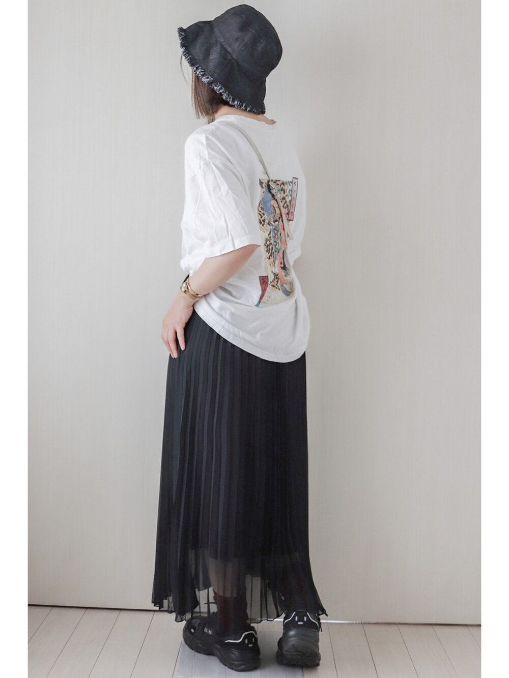 ホワイト系のTシャツ/カットソー、ブラック系のスカート、ブラック系のスニーカーを着用したレディースの夏コーディネートの2枚目の写真