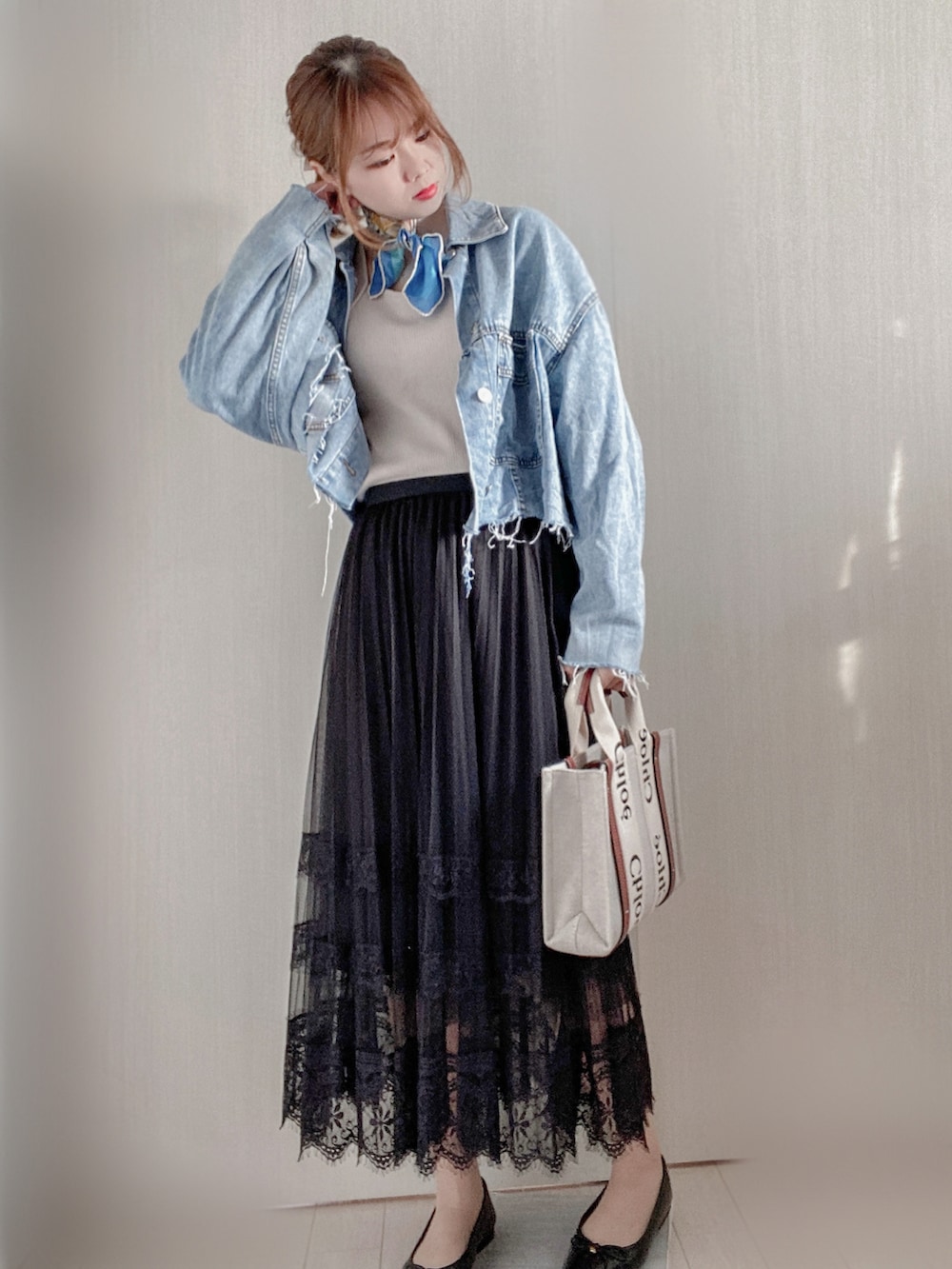 ブルー系のデニムジャケット、ブラウン系のトートバッグ、ブラック系のパンプスを着用したレディースの春コーディネートの2枚目の写真