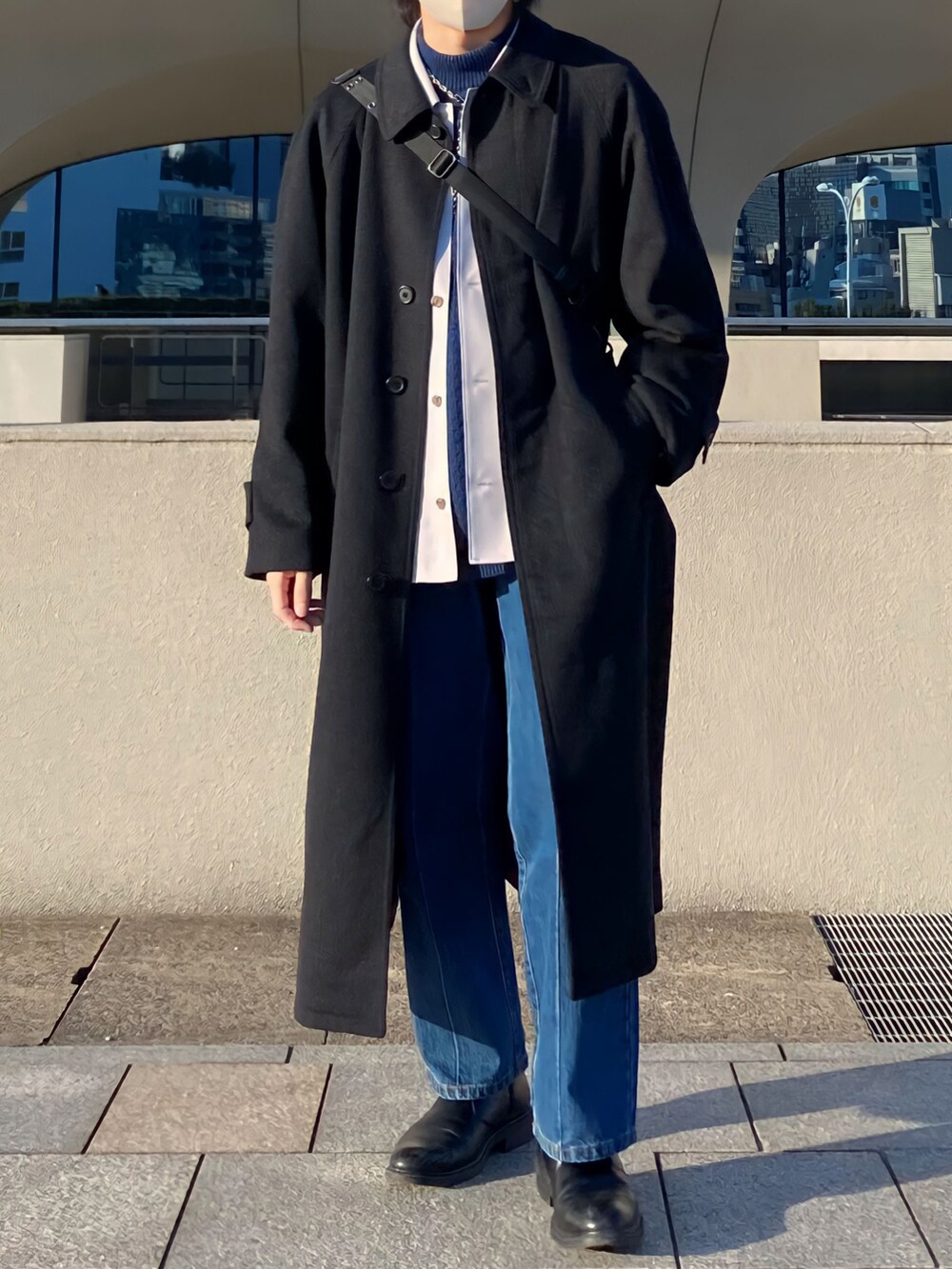 ブラック系のステンカラーコート、ブルー系のシャツ/ブラウス、ブルー系のニット/セーターを着用したメンズの冬コーディネートの2枚目の写真