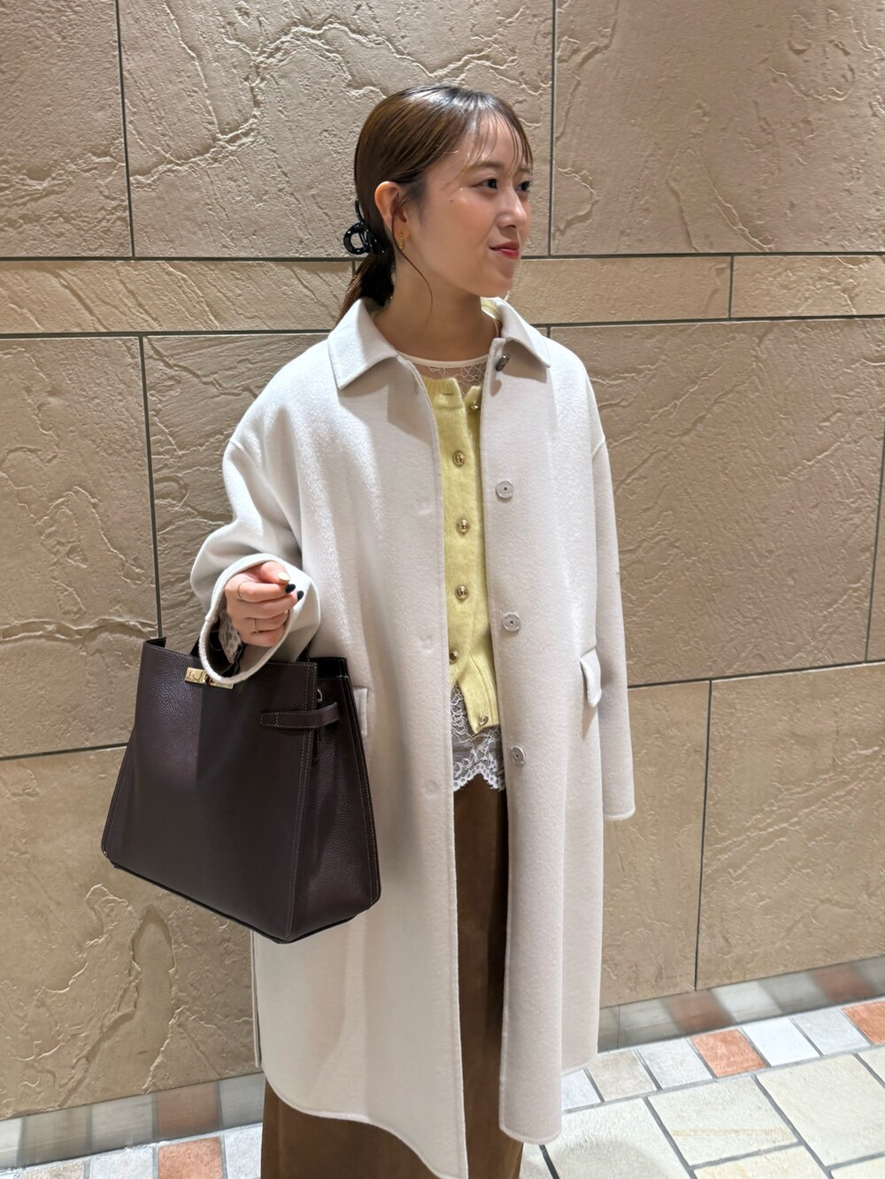 イエロー系のカーディガン/ボレロ、ホワイト系のシャツ/ブラウス、イエロー系のスカートを着用したレディースの秋コーディネートの6枚目の写真