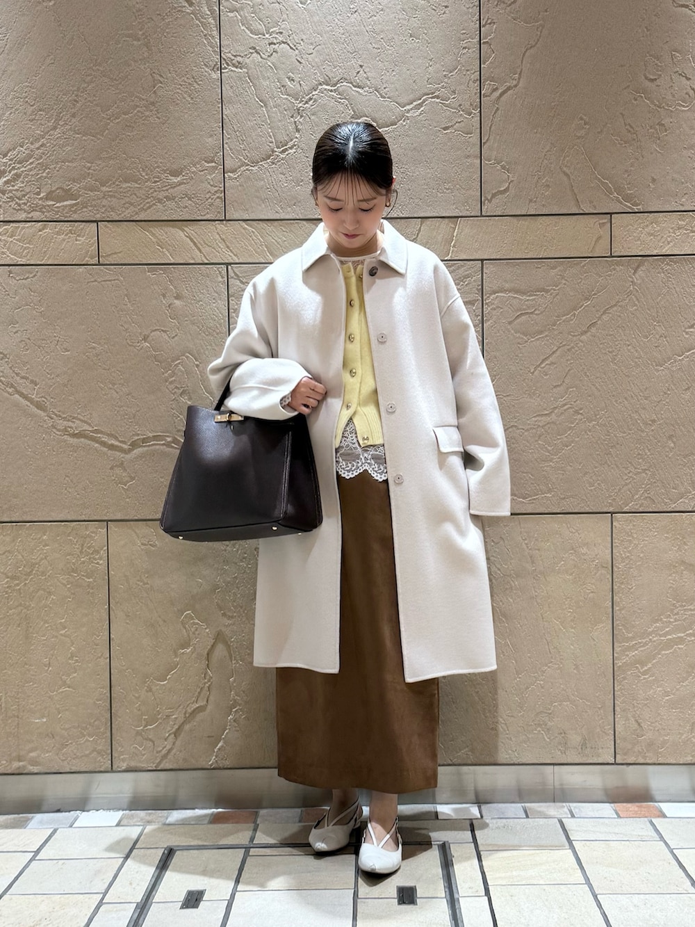 イエロー系のカーディガン/ボレロ、ホワイト系のシャツ/ブラウス、イエロー系のスカートを着用したレディースの秋コーディネートの2枚目の写真