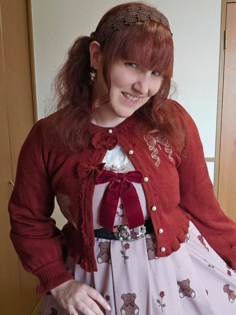 ブラウン系のトートバッグ、ブラウン系のジャンパースカート、レッド系のカーディガン/ボレロを着用したレディースの春コーディネートの3枚目の写真