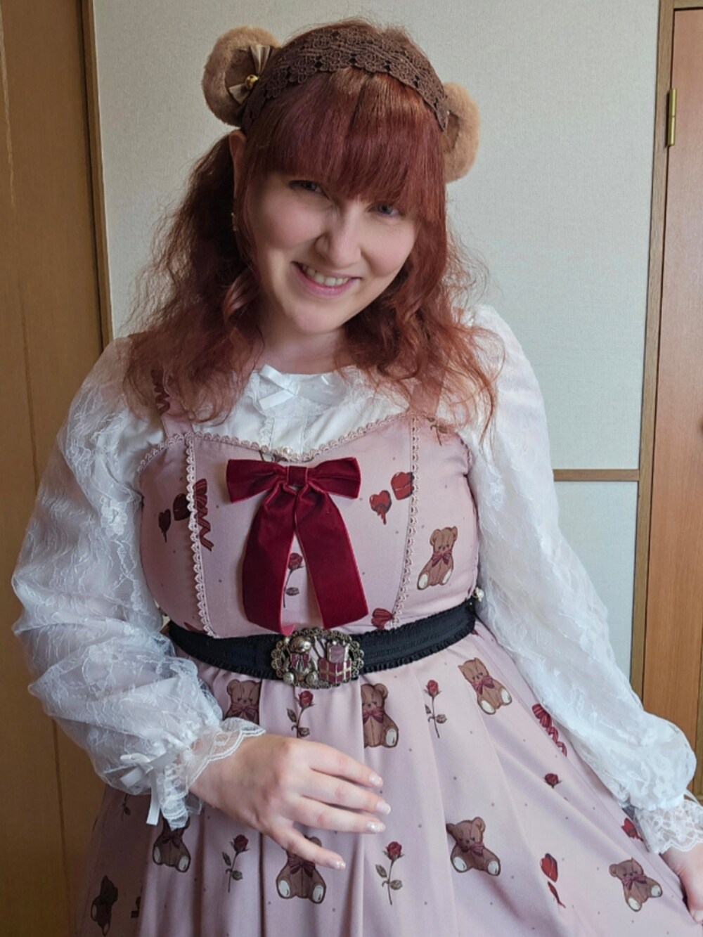 ブラウン系のトートバッグ、ブラウン系のジャンパースカート、レッド系のカーディガン/ボレロを着用したレディースの春コーディネートの4枚目の写真