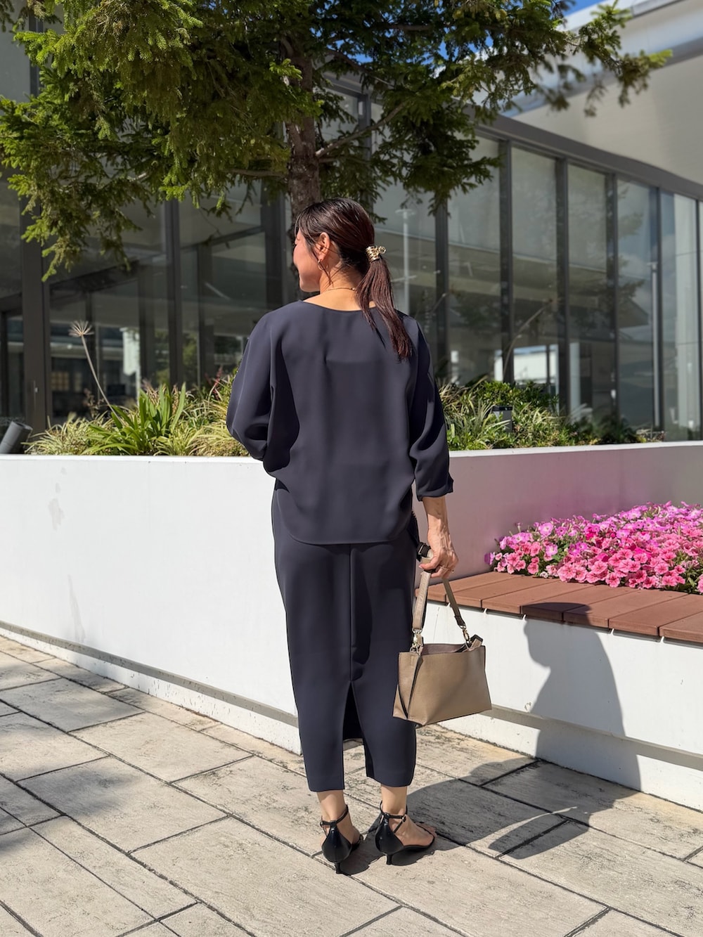 グレー系のシャツ/ブラウス、グレー系のスカート、ベージュ系のショルダーバッグを着用したレディースの夏コーディネートの3枚目の写真