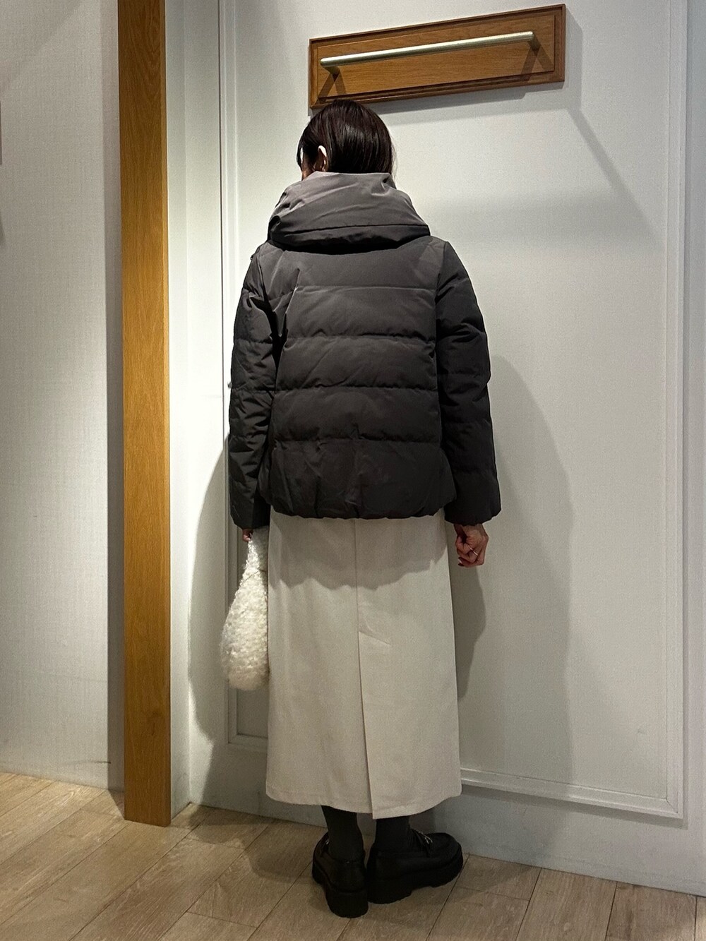 ピンク系のニット/セーター、ホワイト系のスカート、グレー系のダウンジャケット/コートを着用したレディースの冬コーディネートの9枚目の写真