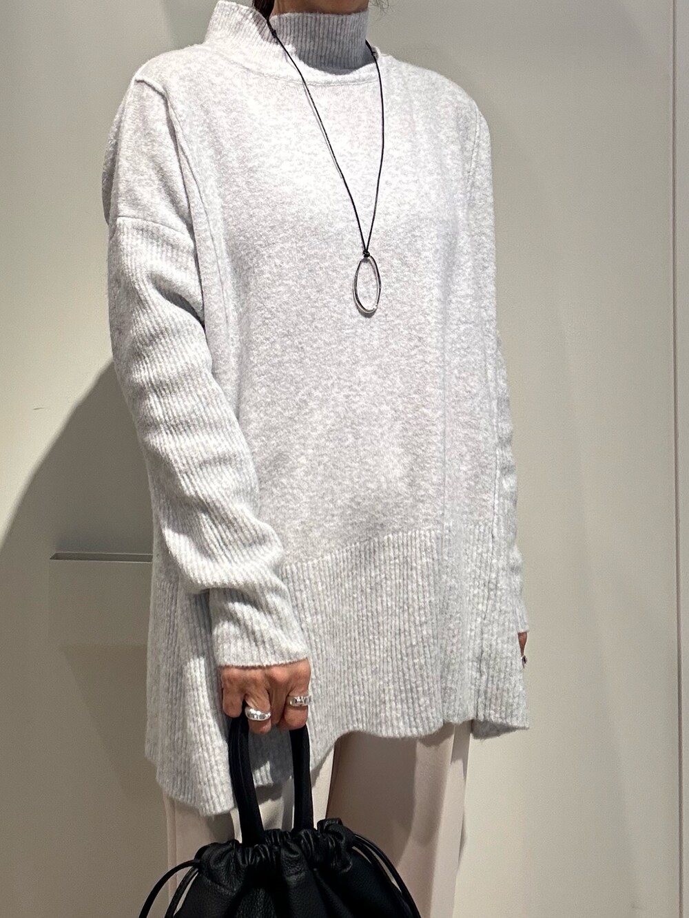 グレー系のニット/セーター、ホワイト系のその他パンツ、ブラック系のショルダーバッグを着用したレディースの冬コーディネートの4枚目の写真