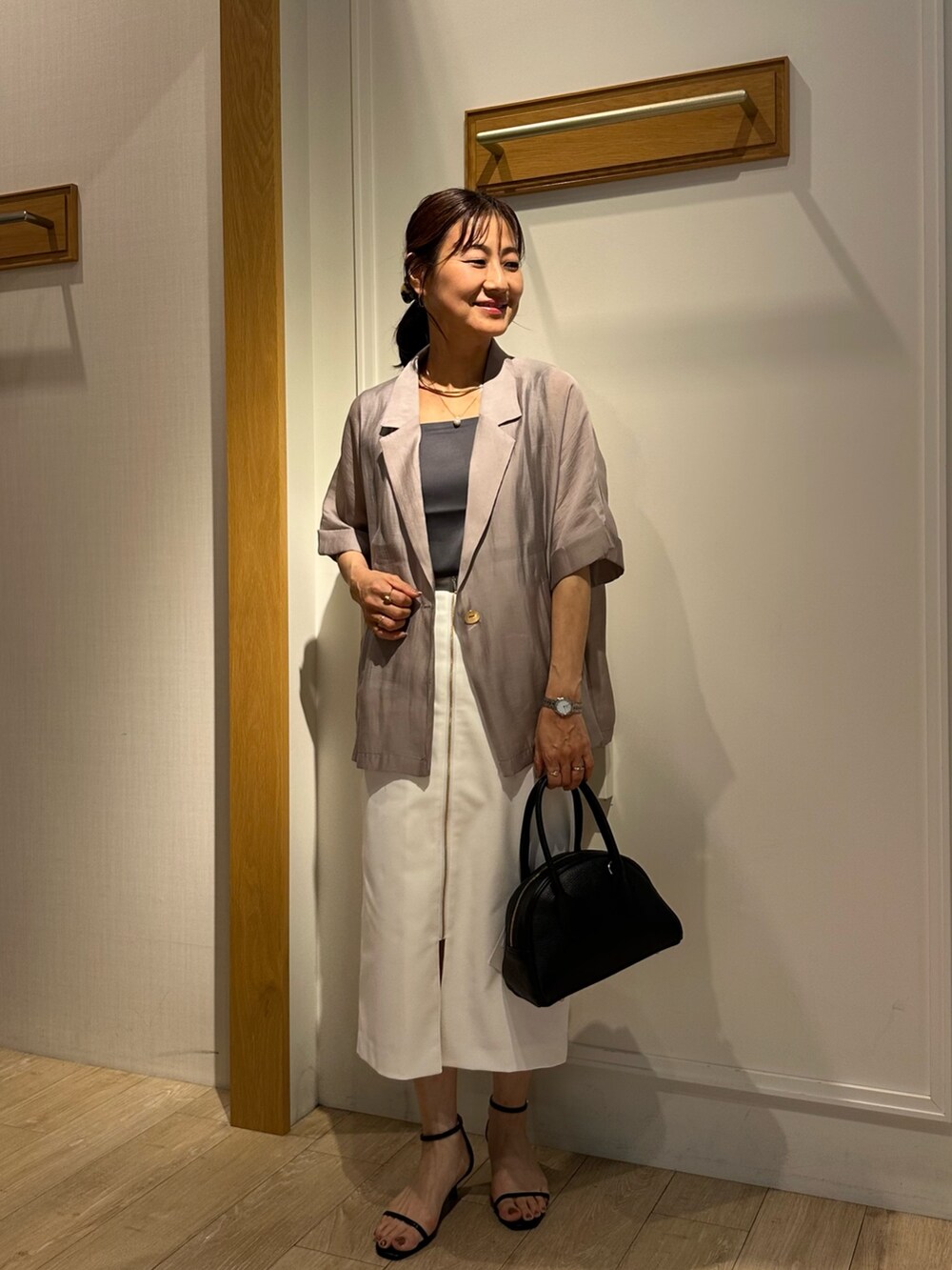 ブラック系のサンダル、グレー系のTシャツ/カットソー、ホワイト系のスカートを着用したレディースの夏コーディネートの5枚目の写真