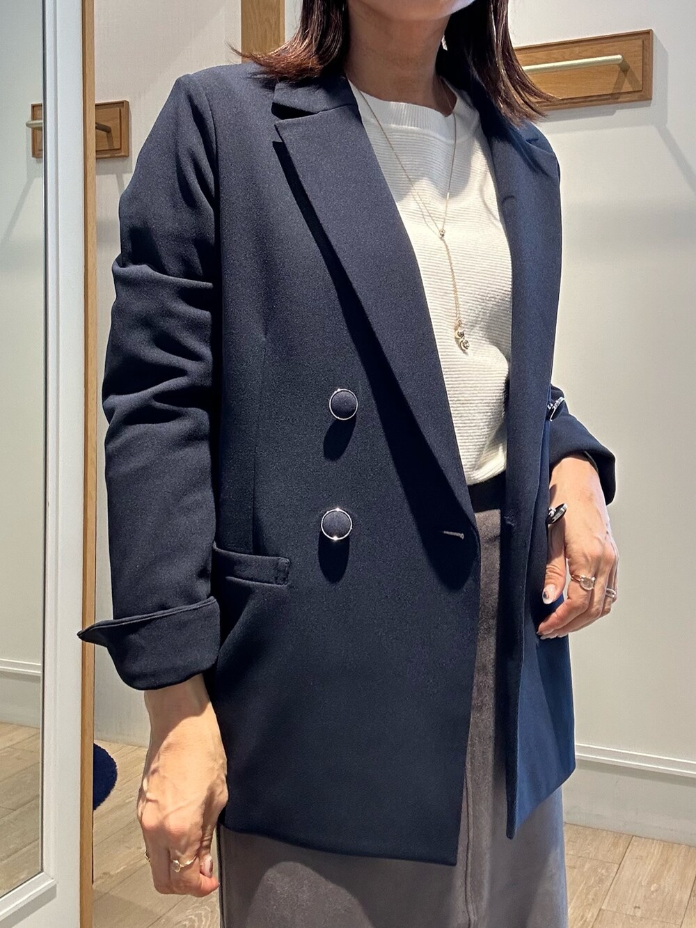 ホワイト系のニット/セーター、ブルー系のテーラードジャケット、グレー系のスカートを着用したレディースの秋コーディネートの5枚目の写真