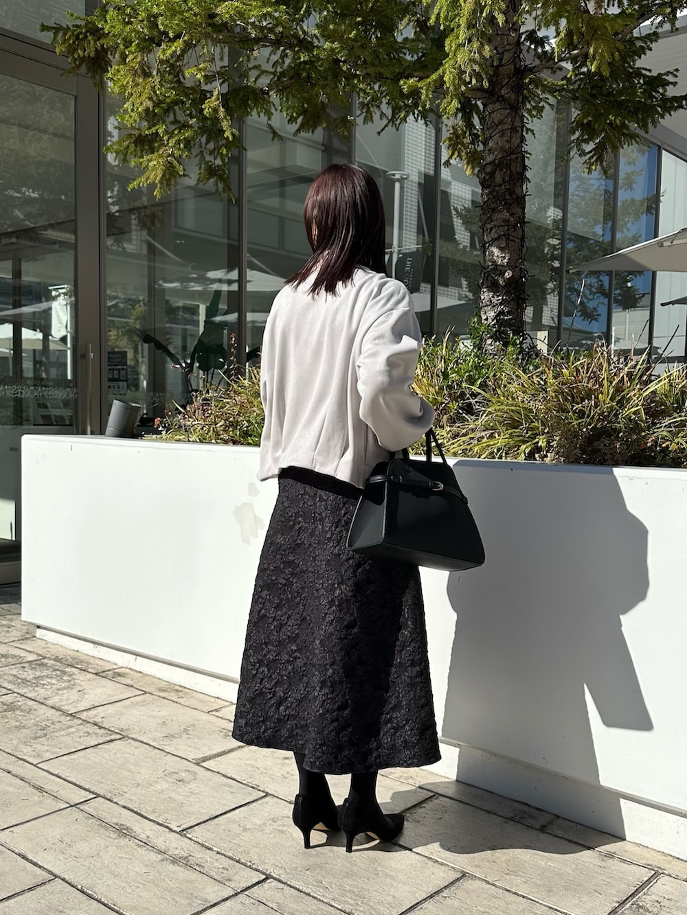 グレー系のブルゾン、ブラック系のニット/セーター、グレー系のスカートを着用したレディースの秋コーディネートの3枚目の写真