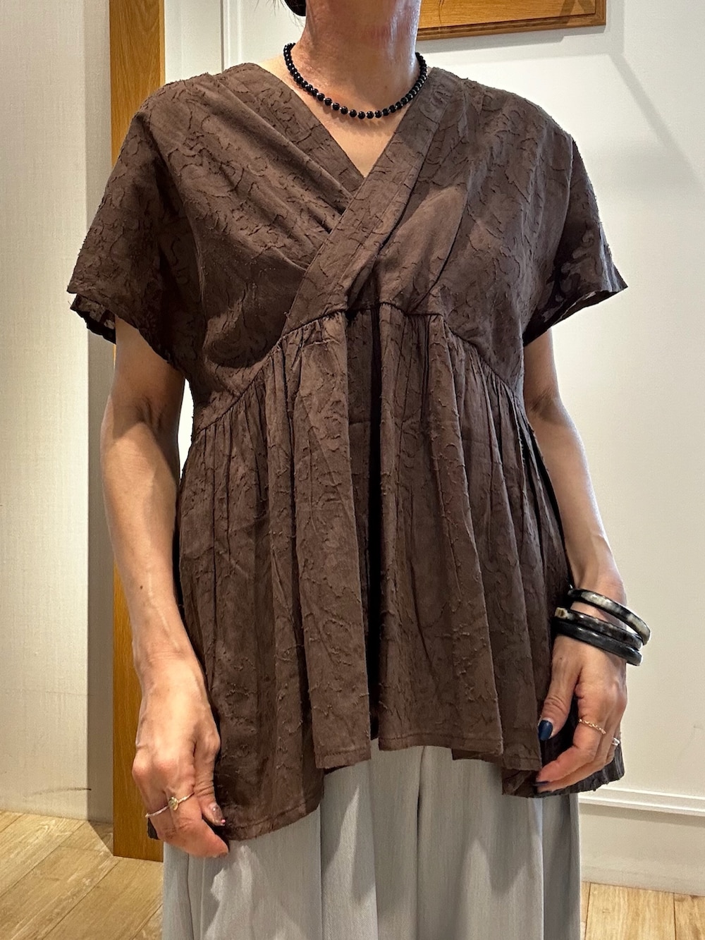 ブラウン系のシャツ/ブラウス、グレー系のその他パンツ、ゴールド系のトートバッグを着用したレディースの夏コーディネートの5枚目の写真