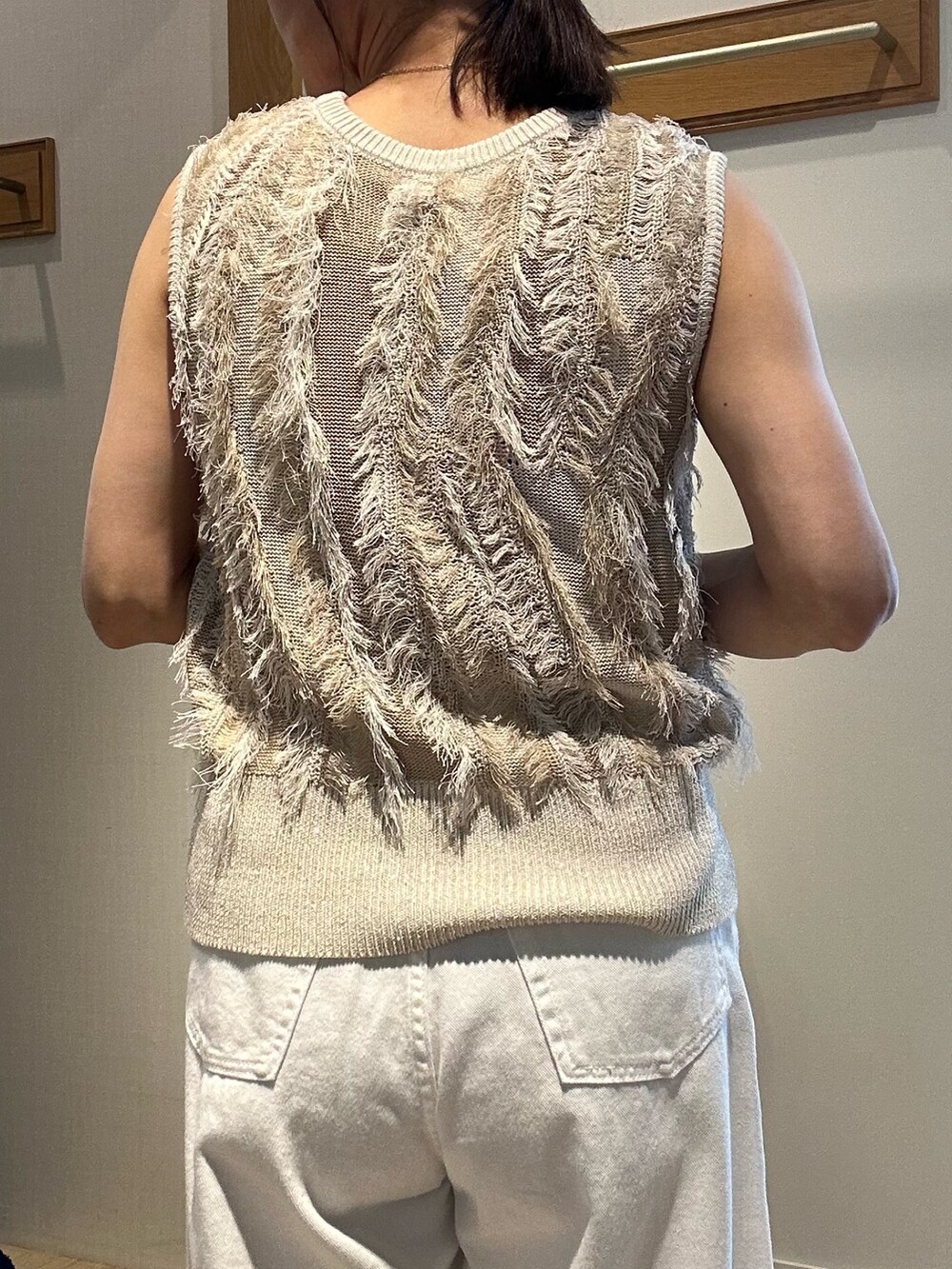 ベージュ系のニット/セーター、ホワイト系のデニムパンツ、ゴールド系のヘアゴムを着用したレディースの夏コーディネートの10枚目の写真