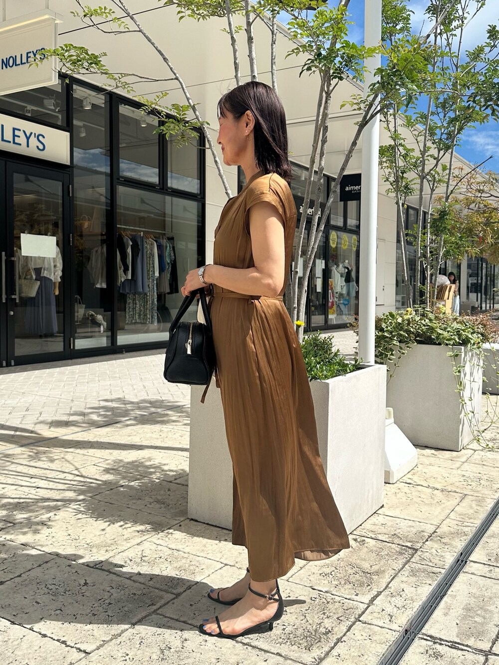 ブラウン系のワンピース、ブラック系のボストンバッグ、ブラック系のサンダルを着用したレディースの夏コーディネートの2枚目の写真