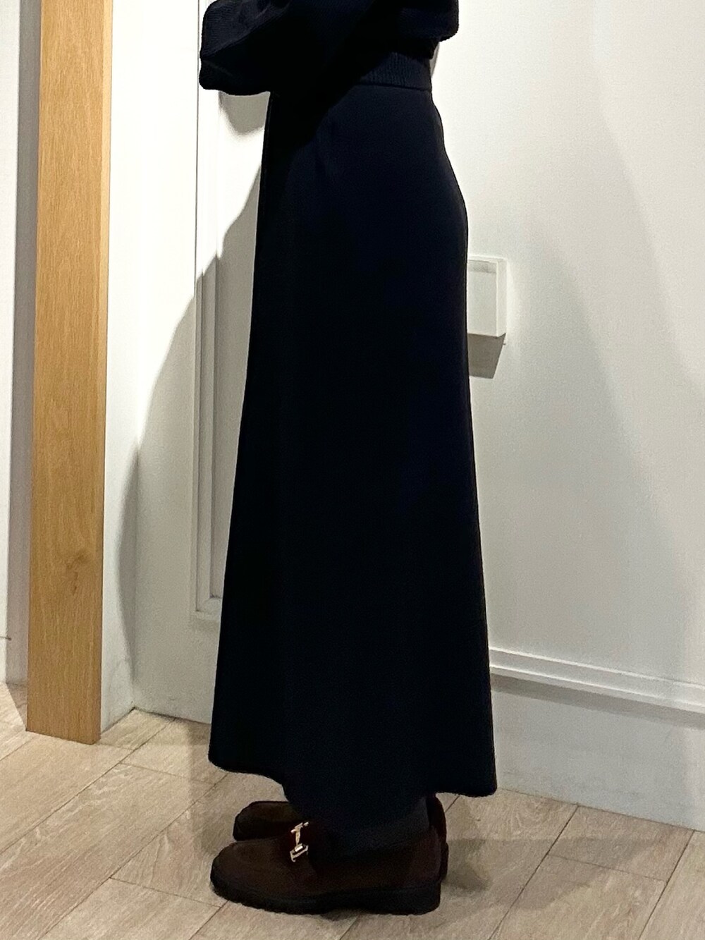 ホワイト系のトートバッグ、ブラウン系のローファー、ブルー系のニット/セーターを着用したレディースの冬コーディネートの7枚目の写真