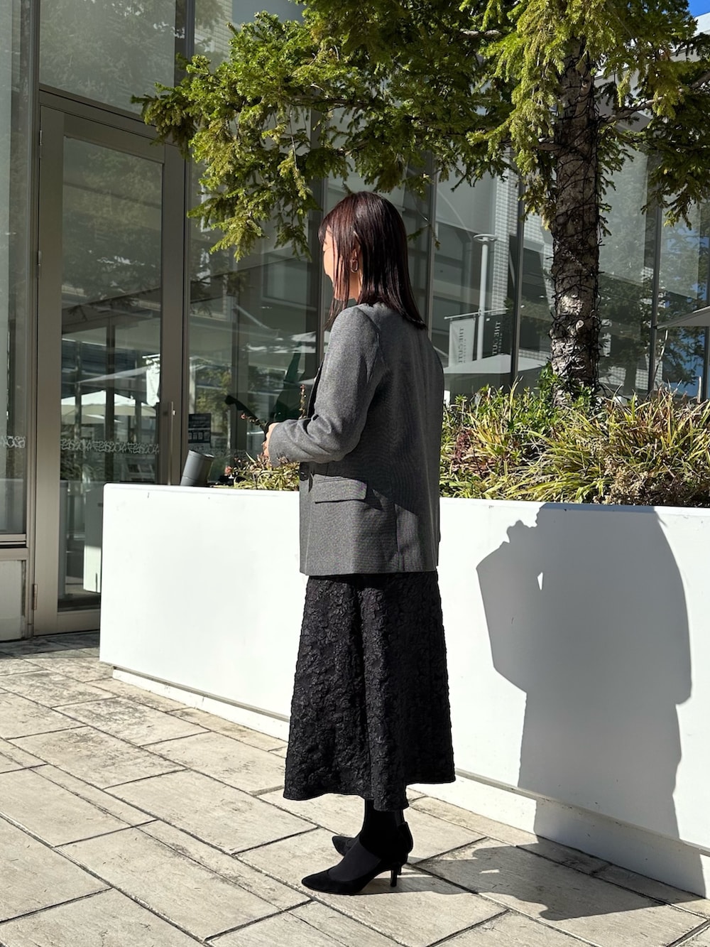 グレー系のテーラードジャケット、ブラック系のニット/セーター、グレー系のスカートを着用したレディースの秋コーディネートの2枚目の写真