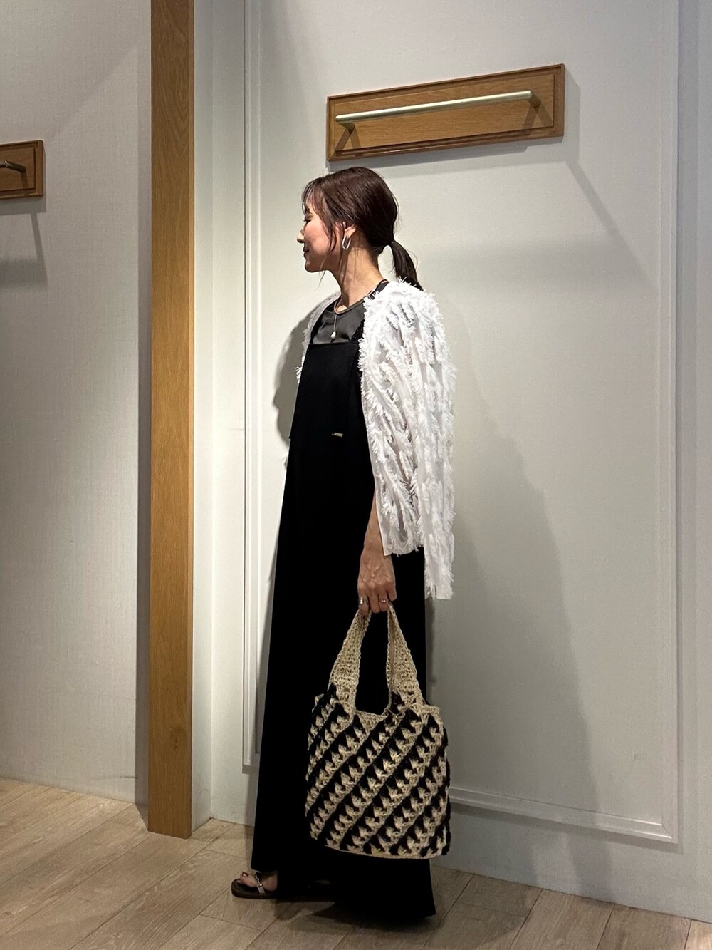 ブラック系のワンピース、ホワイト系のカーディガン/ボレロ、ゴールド系のネックレスを着用したレディースの夏コーディネートの9枚目の写真