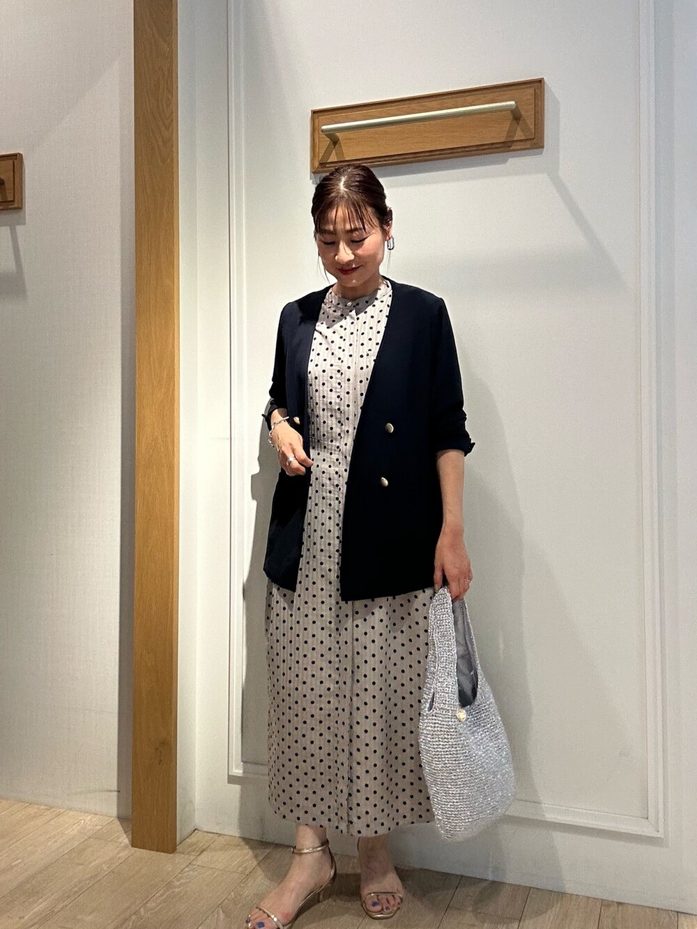 ベージュ系のワンピース、ブルー系のノーカラージャケットを着用したレディースの夏コーディネートの2枚目の写真