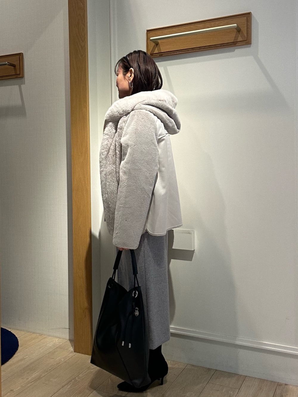 ベージュ系のムートンコート、ブルー系のニット/セーター、ホワイト系のニット/セーターを着用したレディースの冬コーディネートの2枚目の写真