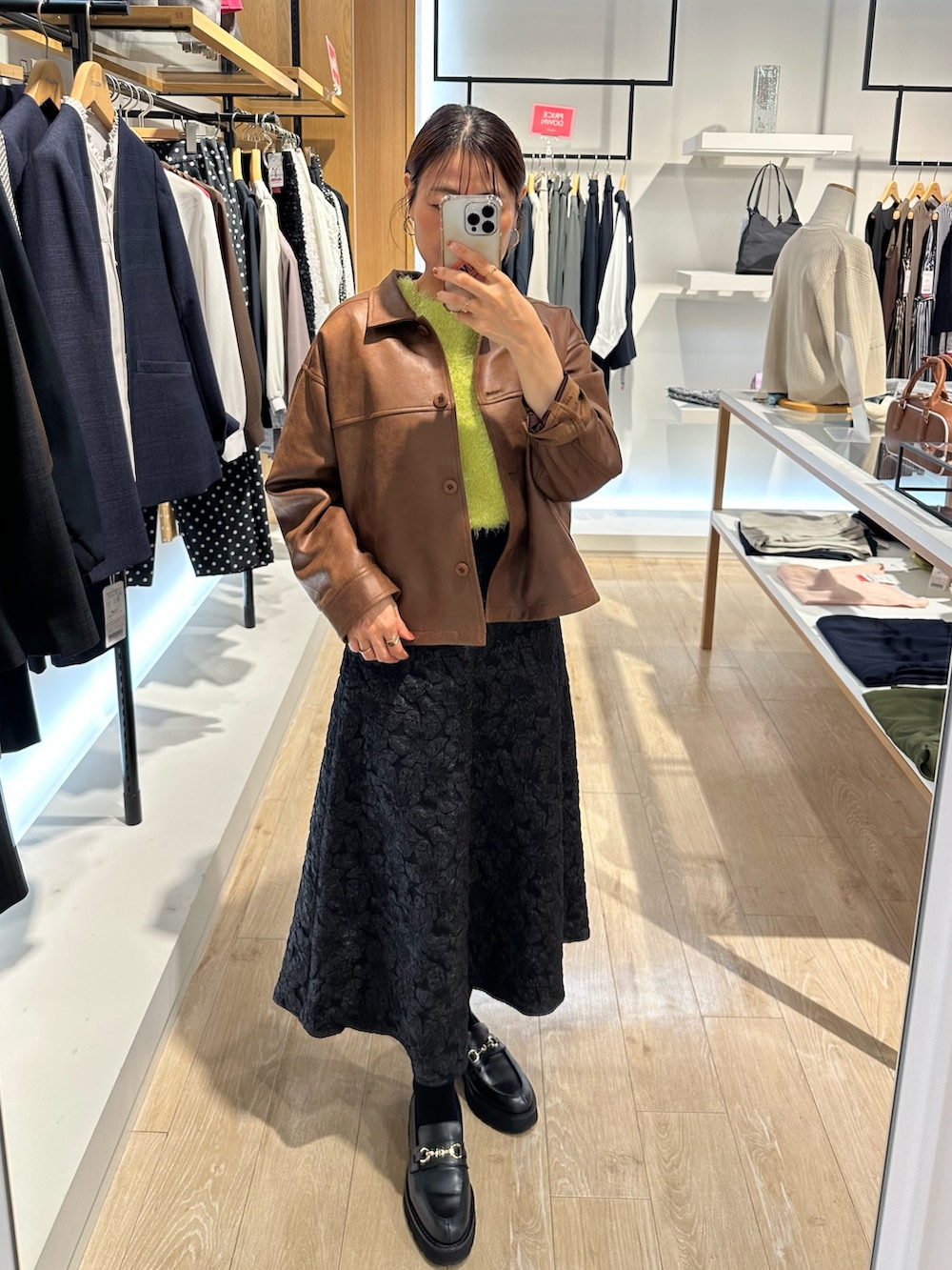 イエロー系のブルゾン、グリーン系のニット/セーター、グレー系のスカートを着用したレディースの秋コーディネートの9枚目の写真