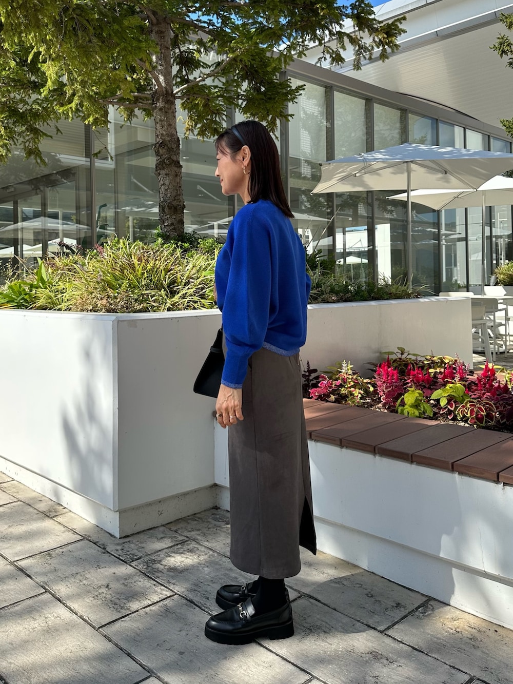 ブルー系のテーラードジャケット、ブルー系のニット/セーター、グレー系のスカートを着用したレディースの秋コーディネートの7枚目の写真