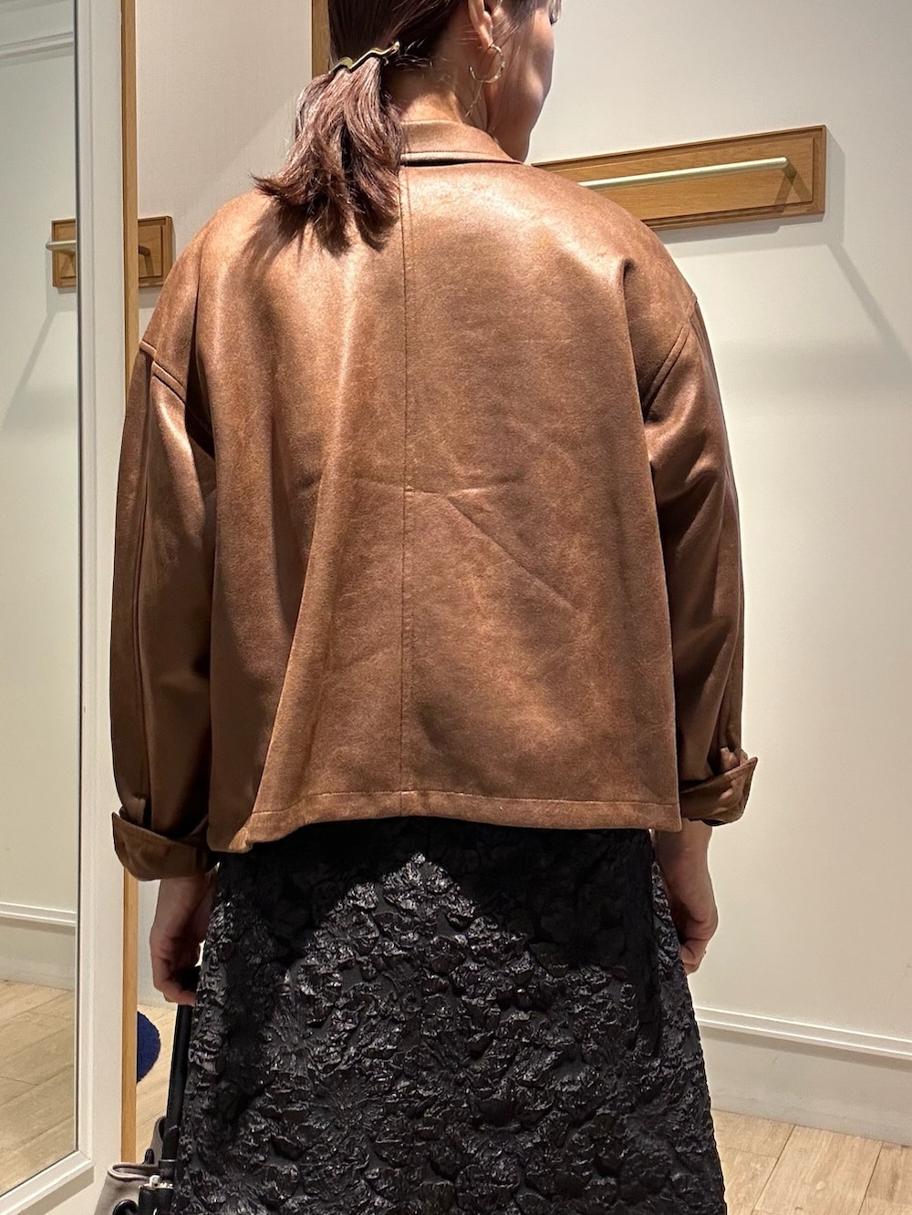 イエロー系のブルゾン、グリーン系のニット/セーター、グレー系のスカートを着用したレディースの秋コーディネートの7枚目の写真