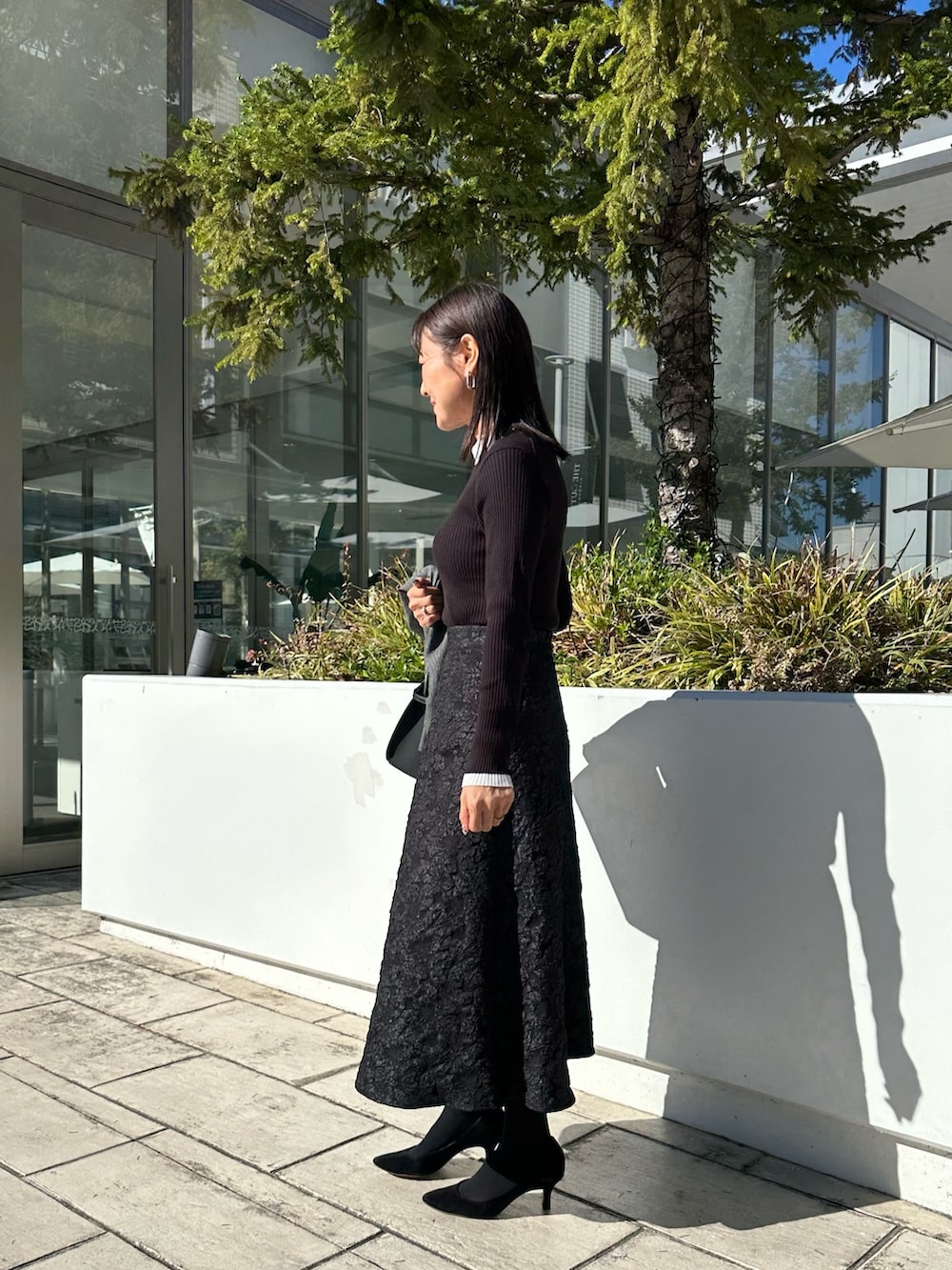 ブラック系のトートバッグ、グレー系のテーラードジャケット、ブラック系のニット/セーターを着用したレディースの秋コーディネートの2枚目の写真