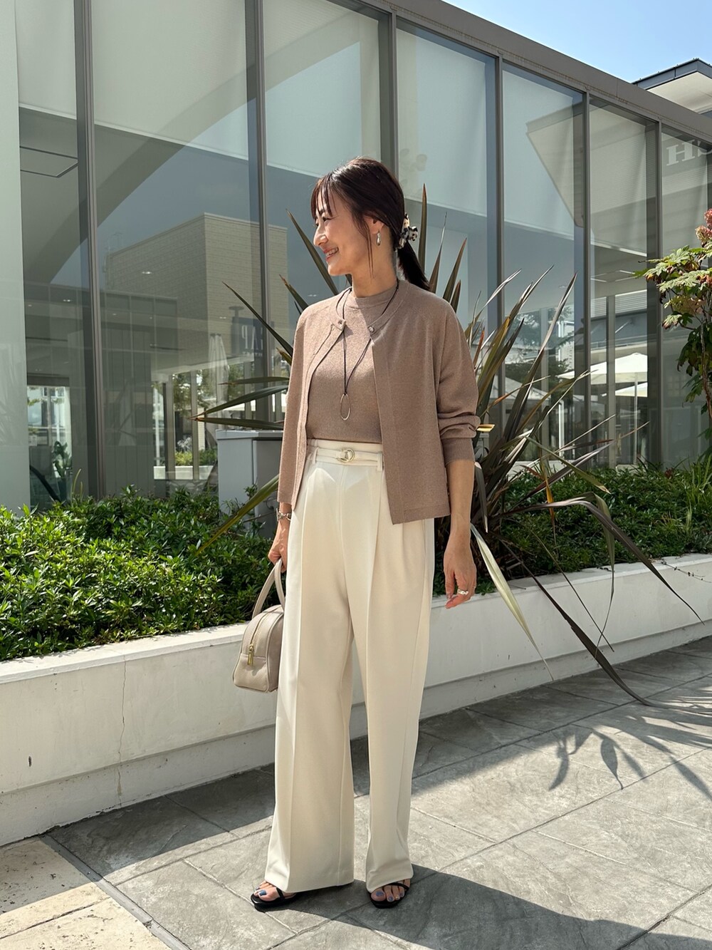 ブラウン系のニット/セーター、ホワイト系のその他パンツ、ベージュ系のボストンバッグを着用したレディースの夏コーディネートの2枚目の写真