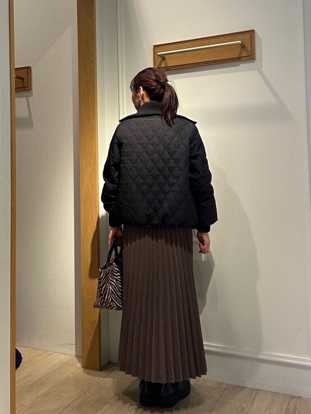 ブラウン系のブルゾン、ホワイト系のニット/セーター、ブラウン系のスカートを着用したレディースの秋コーディネートの2枚目の写真