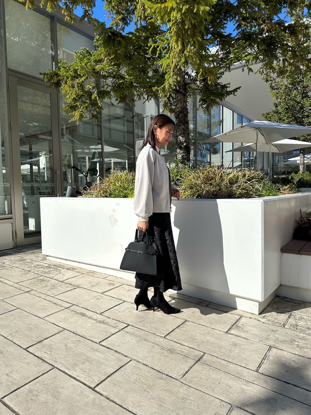 グレー系のブルゾン、ブラック系のニット/セーター、グレー系のスカートを着用したレディースの秋コーディネートの5枚目の写真