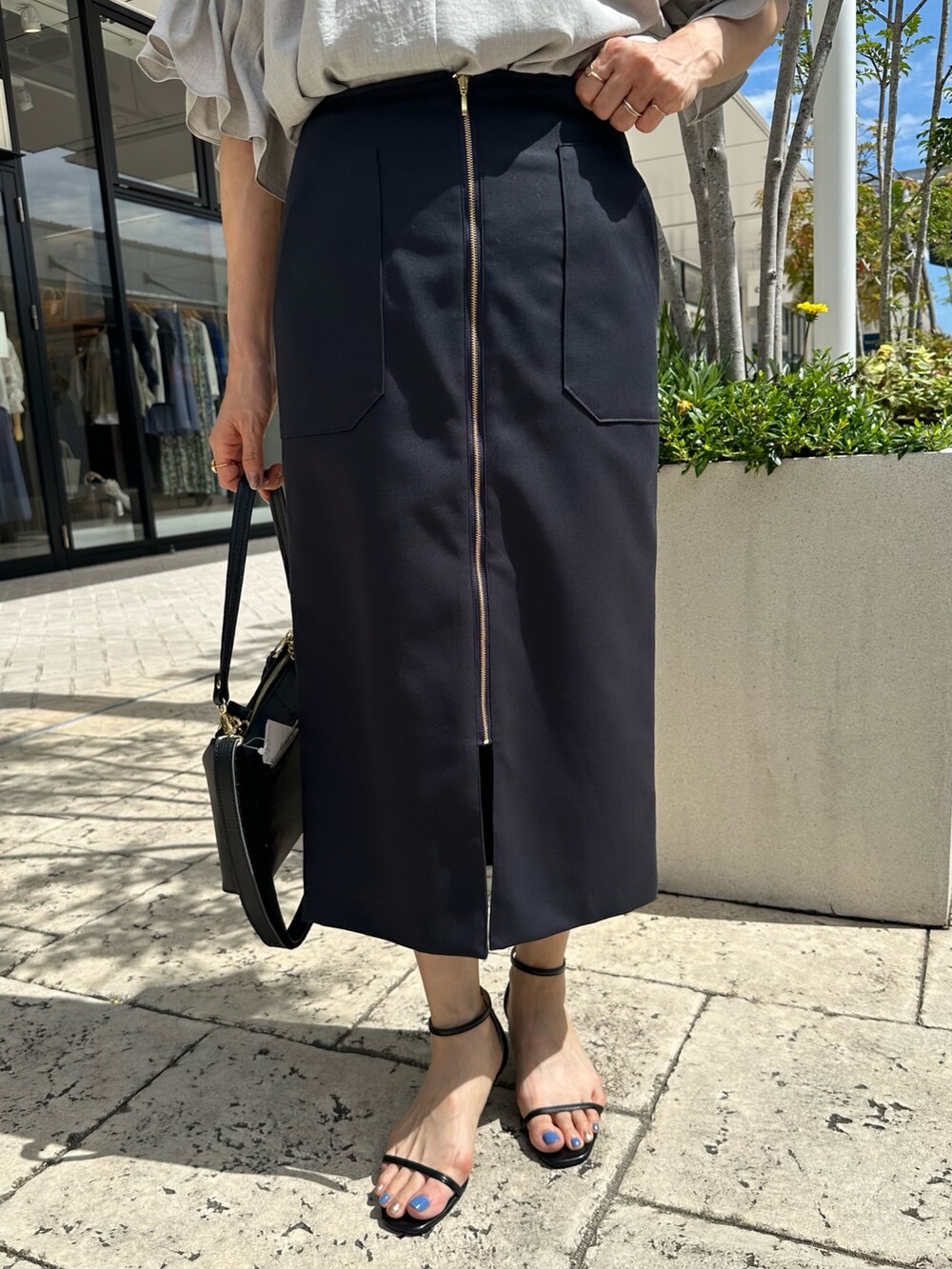 ブラック系のサンダル、ベージュ系のシャツ/ブラウス、ブルー系のスカートを着用したレディースの夏コーディネートの7枚目の写真