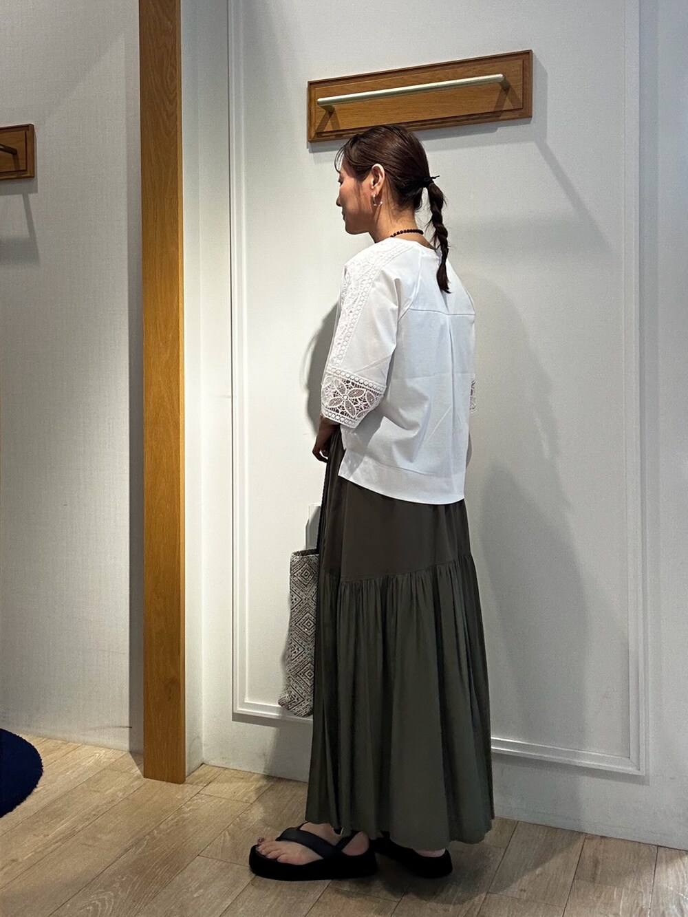 ホワイト系のTシャツ/カットソー、ブラック系のトートバッグ、グリーン系のスカートを着用したレディースの夏コーディネートの2枚目の写真