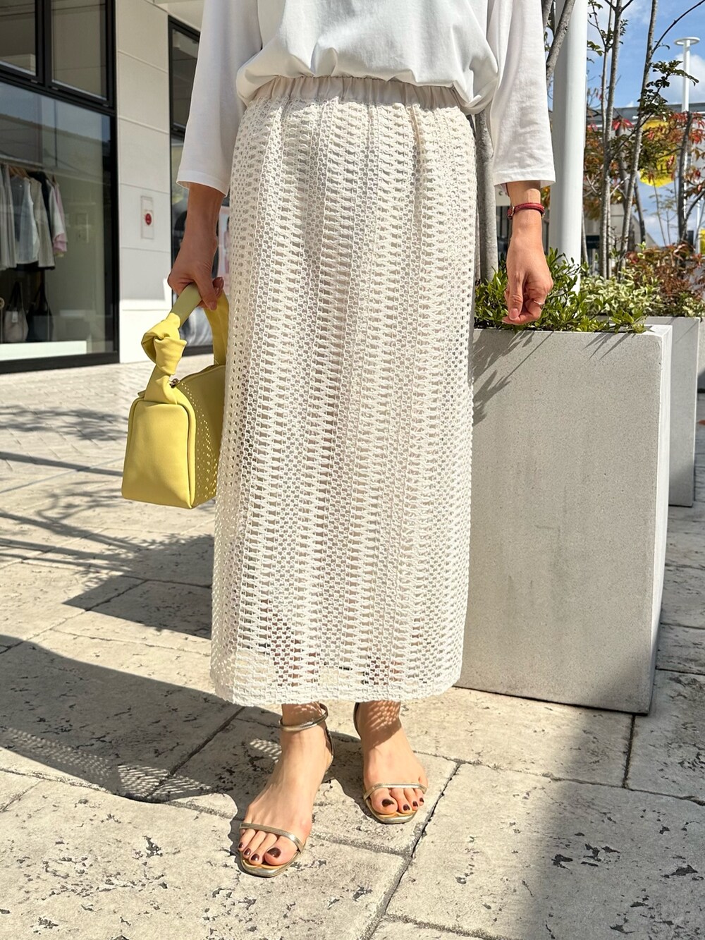 ブルー系のテーラードジャケット、ホワイト系のスカート、イエロー系のショルダーバッグを着用したレディースの春コーディネートの10枚目の写真