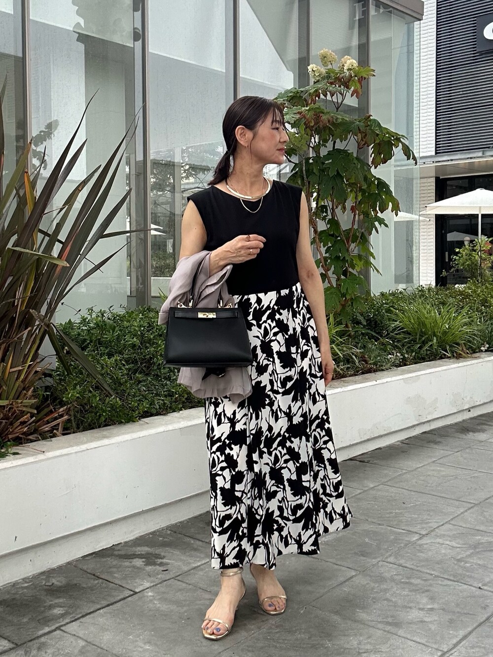 ホワイト系のワンピース、ブラック系のショルダーバッグ、ベージュ系のテーラードジャケットを着用したレディースの夏コーディネートの5枚目の写真