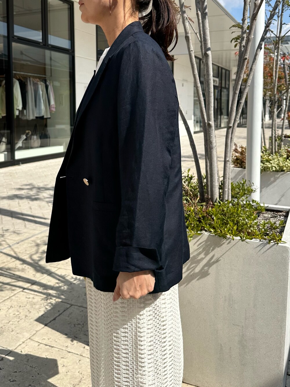 ブルー系のテーラードジャケット、ホワイト系のスカート、イエロー系のショルダーバッグを着用したレディースの春コーディネートの6枚目の写真