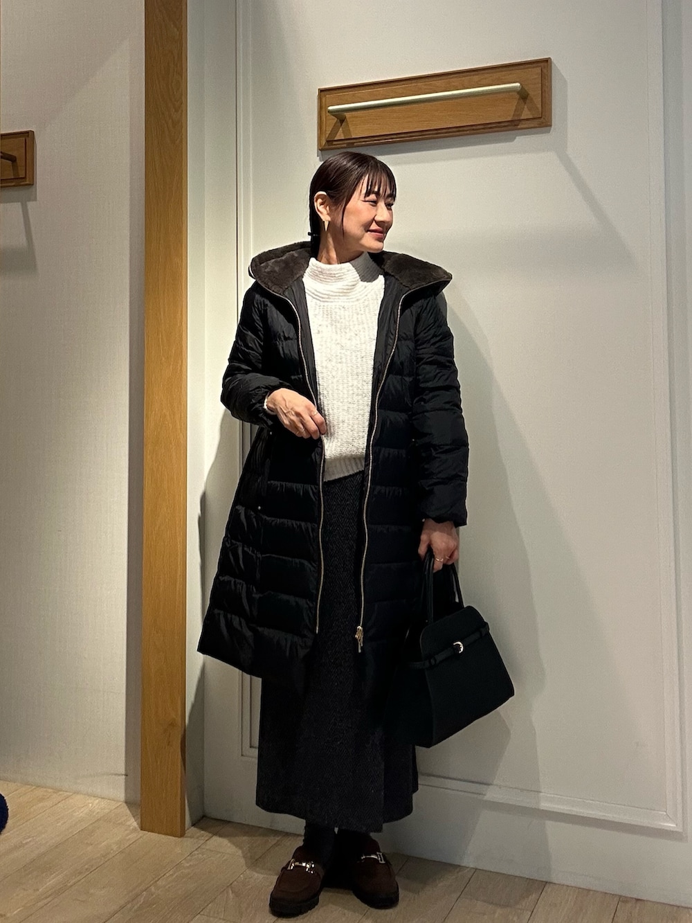ブラック系のダウンジャケット/コート、グレー系のスカート、ブラック系のトートバッグを着用したレディースの冬コーディネートの4枚目の写真