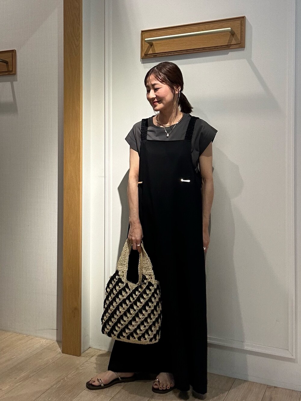 ブラック系のワンピース、ホワイト系のカーディガン/ボレロ、ゴールド系のネックレスを着用したレディースの夏コーディネートの2枚目の写真